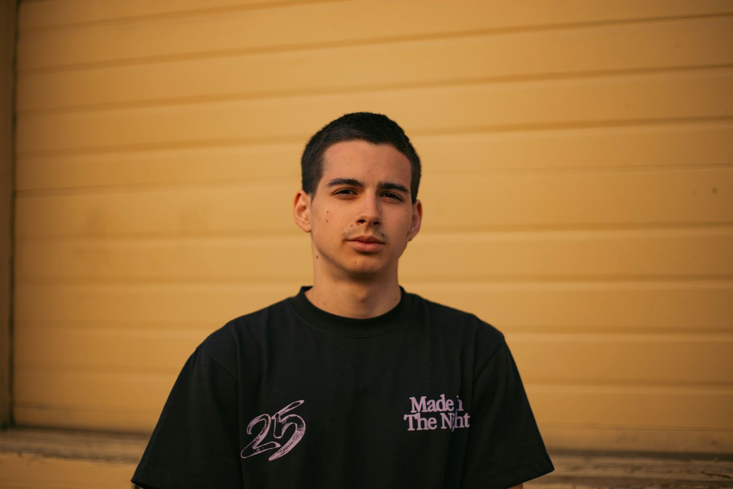 Senior photoshoot of young man with a plain yellow background.