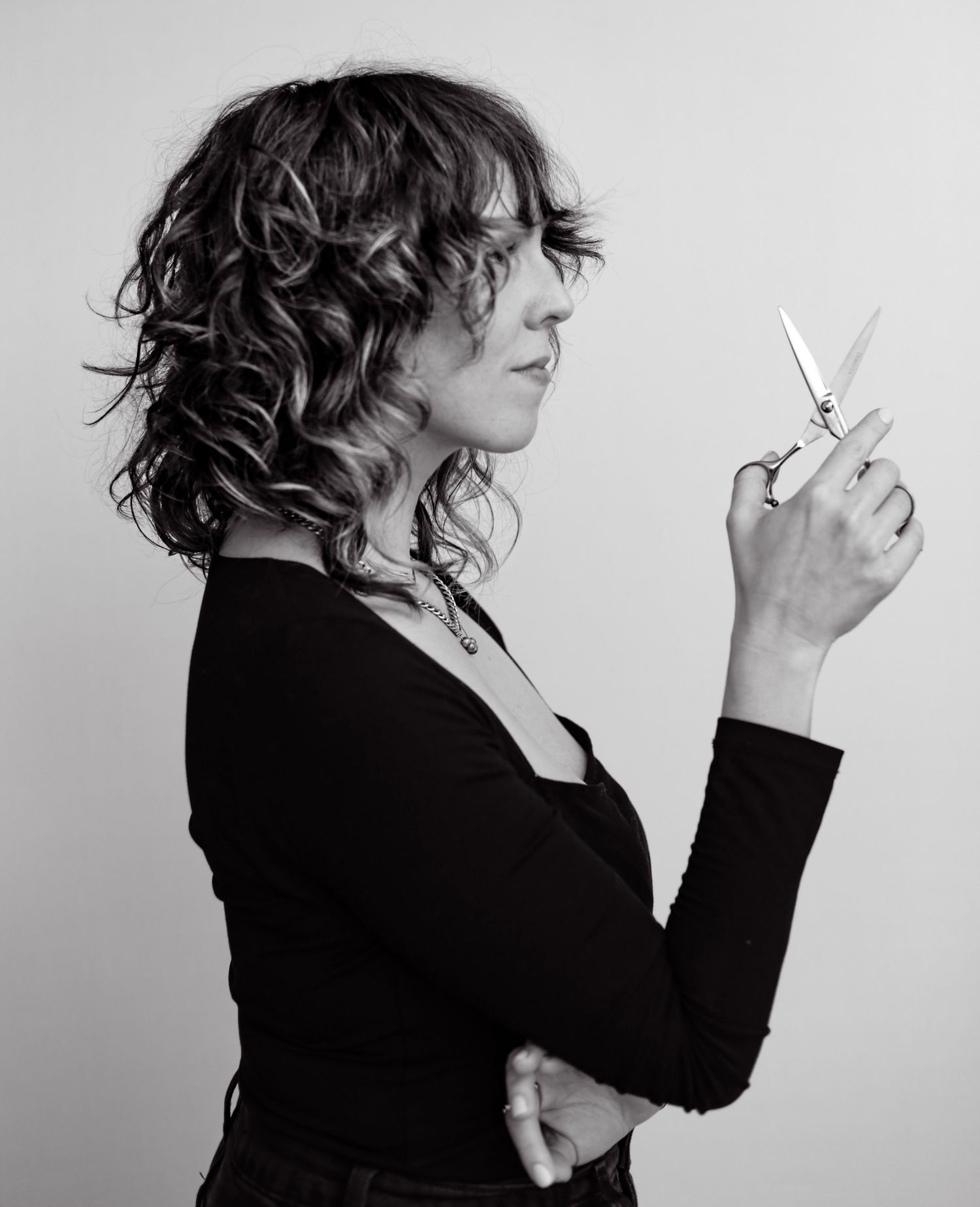 Woman holding hair cutting scissors for hair styling branding shoot black and white