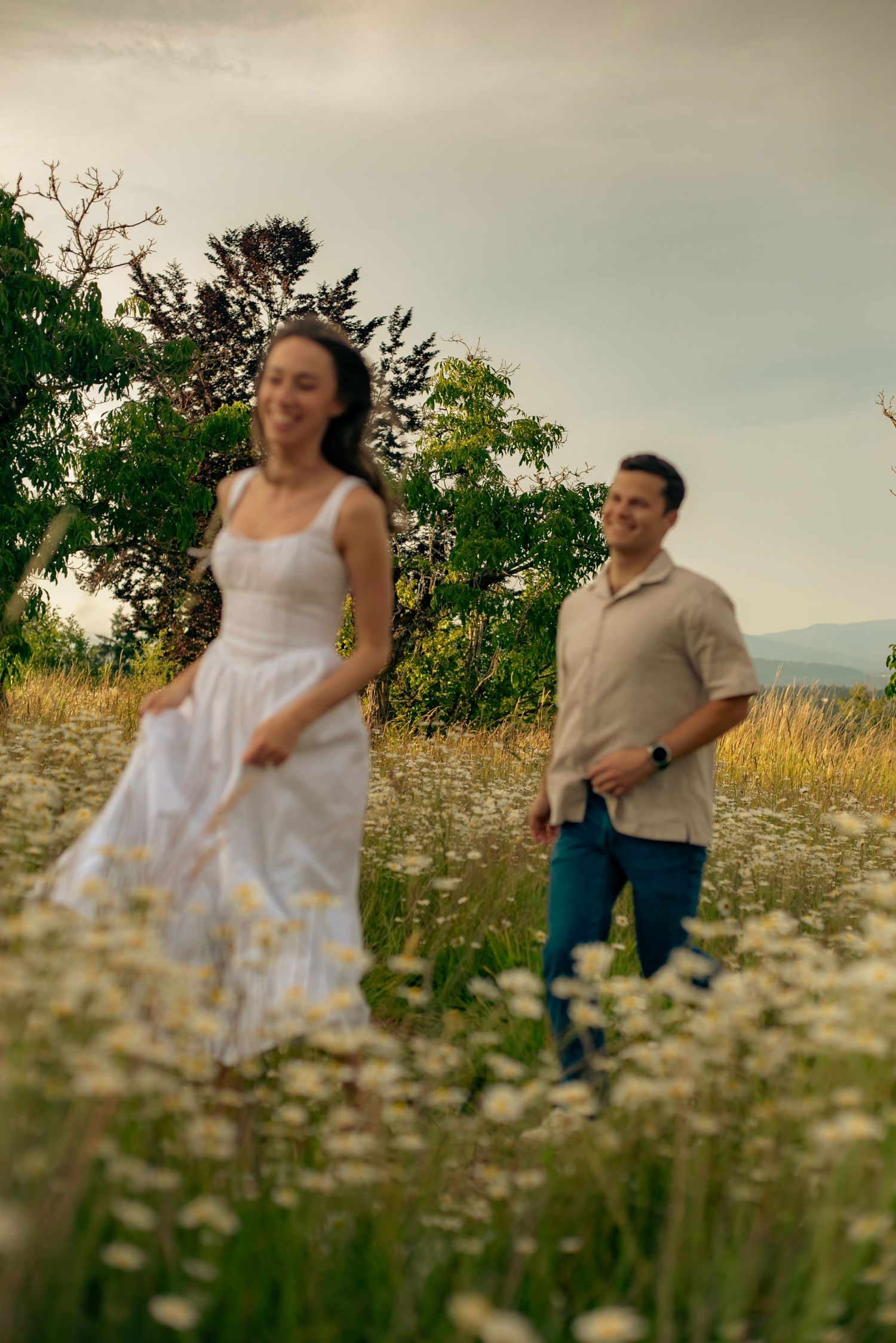 A man playfully chasing a woman in a field of wildflowers