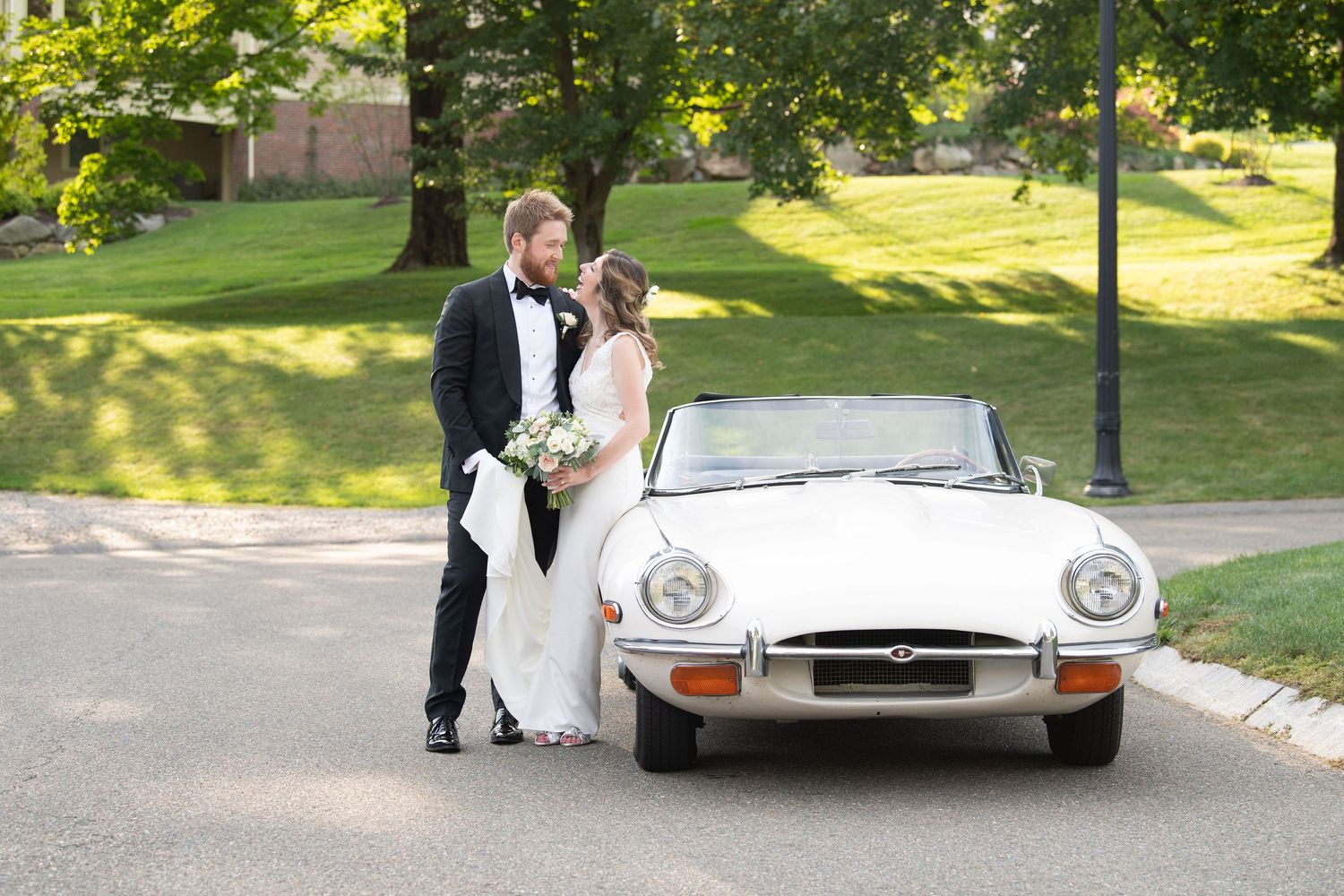 A silver vintage Mercedes Benz convertible parked on a green lawn during a sunny outdoor event.