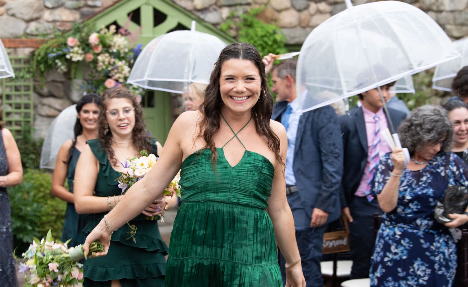 Wedding party members in emerald green and navy dresses celebrating outdoors.