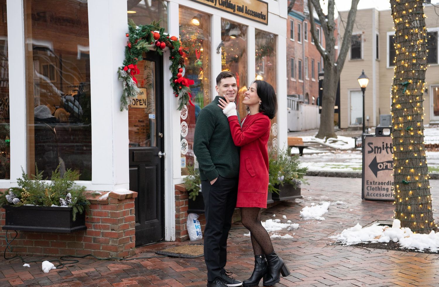 A panoramic view of a snowy street with holiday decorations and people walking along a brick sidewalk in winter.