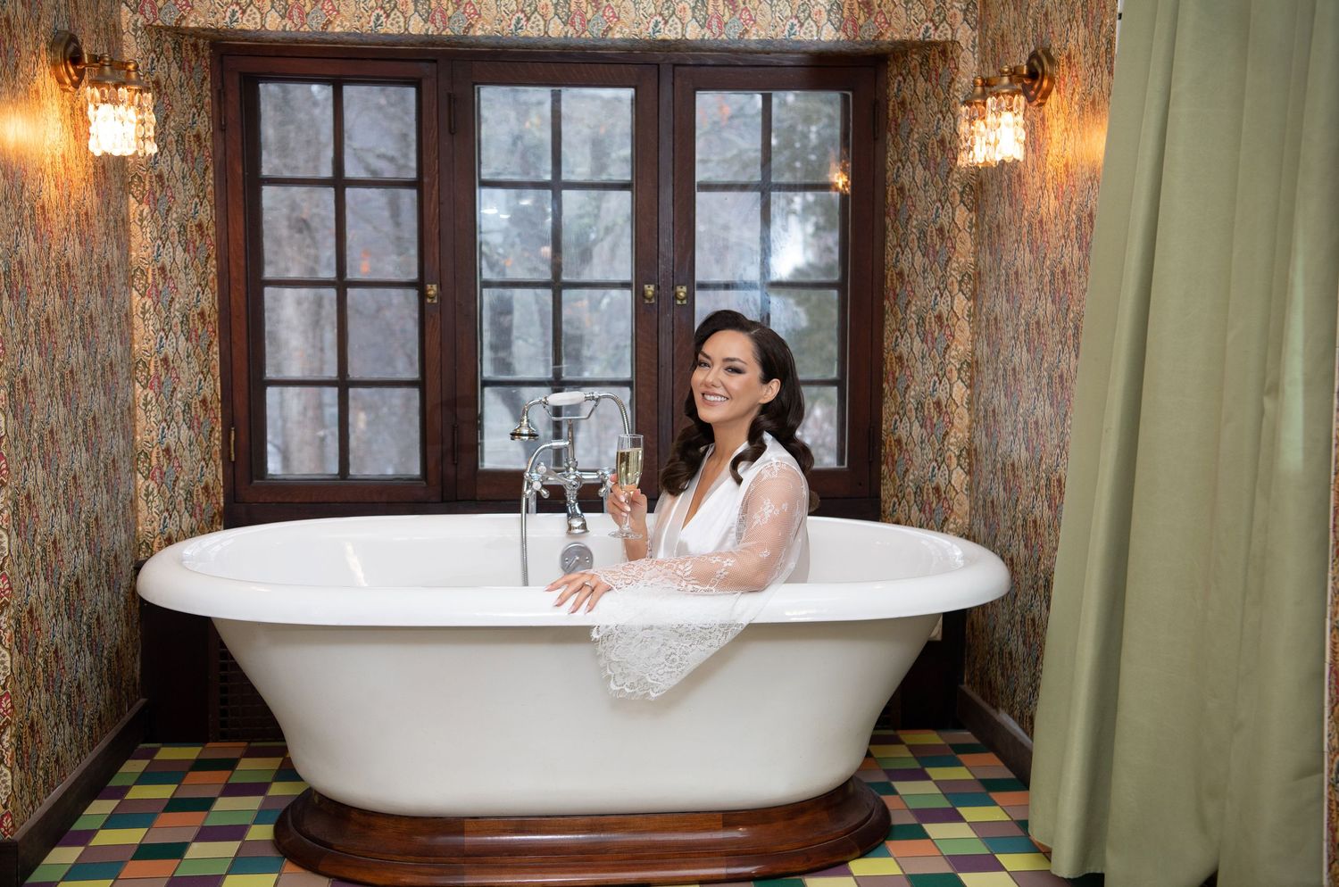 A luxurious clawfoot bathtub sits in an elegant bathroom with vintage wallpaper and warm lighting.