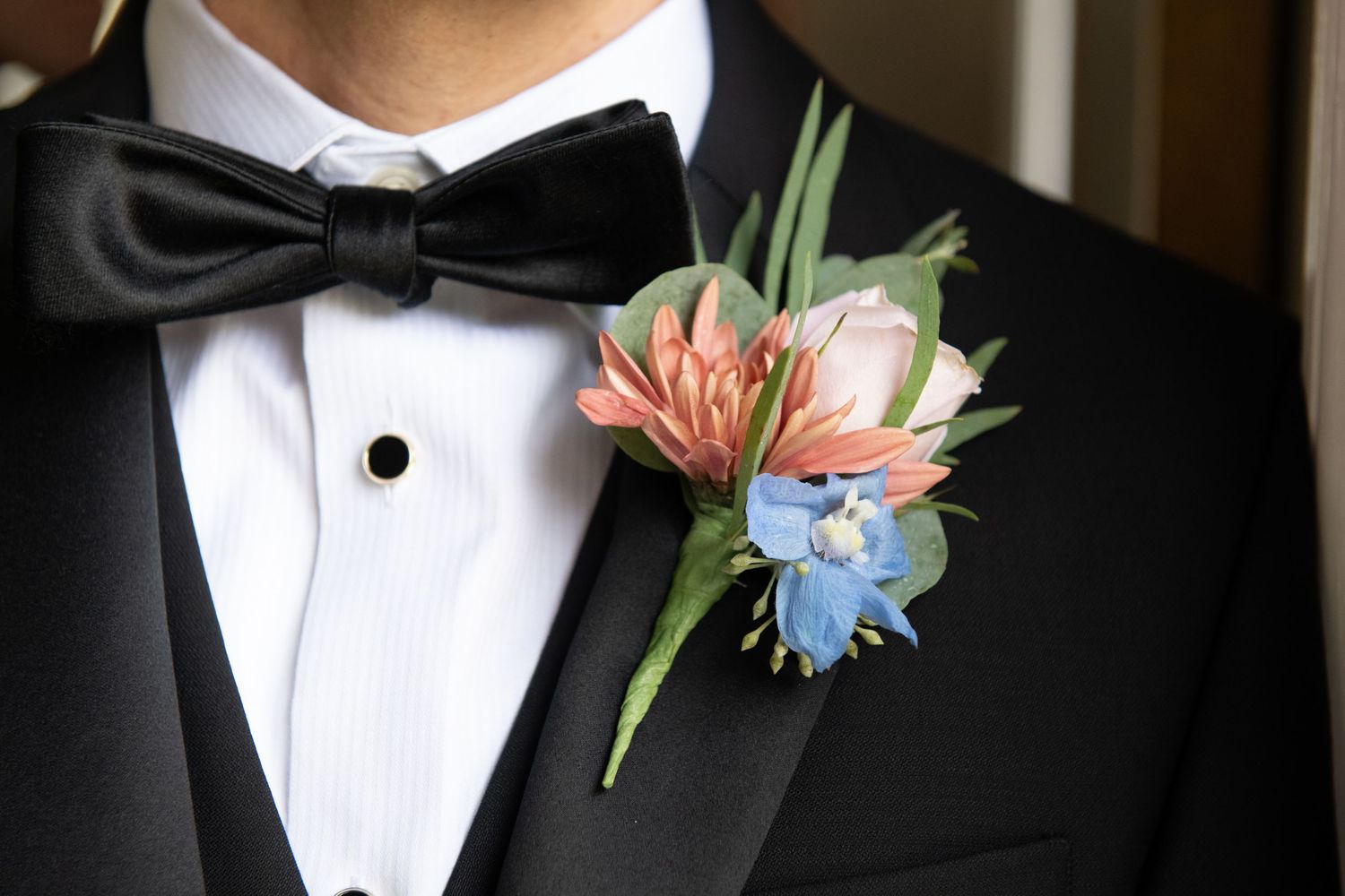 Close-up details of formal black tuxedo with delicate floral boutonniere.