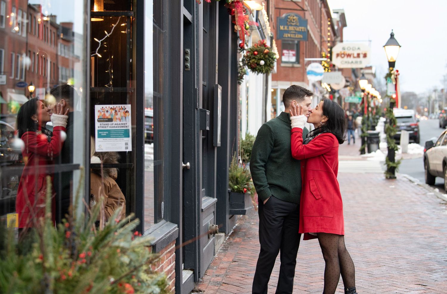 People walking and browsing shops along a brick-paved street with historic storefronts in a downtown area.