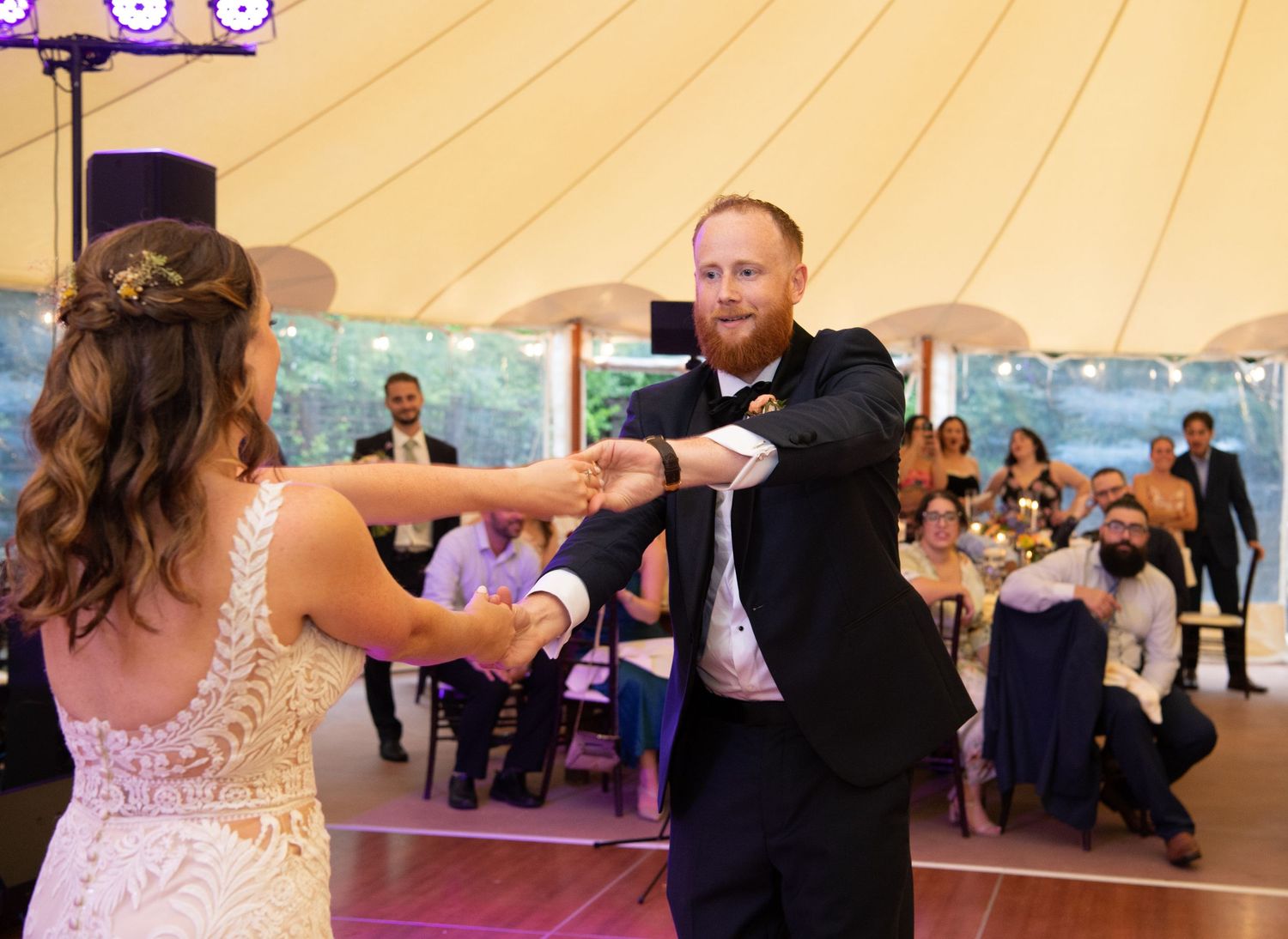 Couple dancing together under a cream-colored tent at their wedding reception.