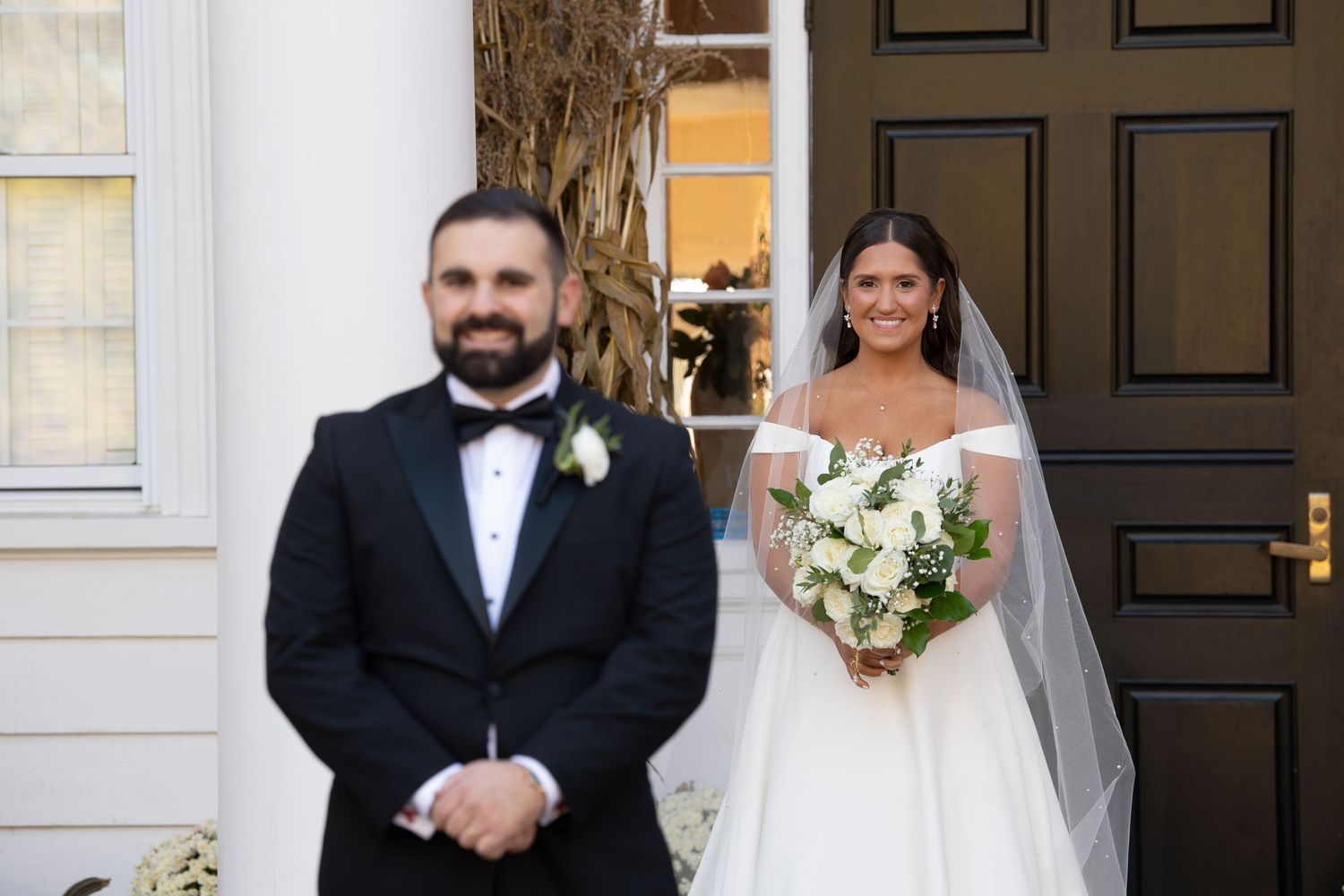Wedding party poses together in formal attire with black and white color scheme in an elegant venue setting.