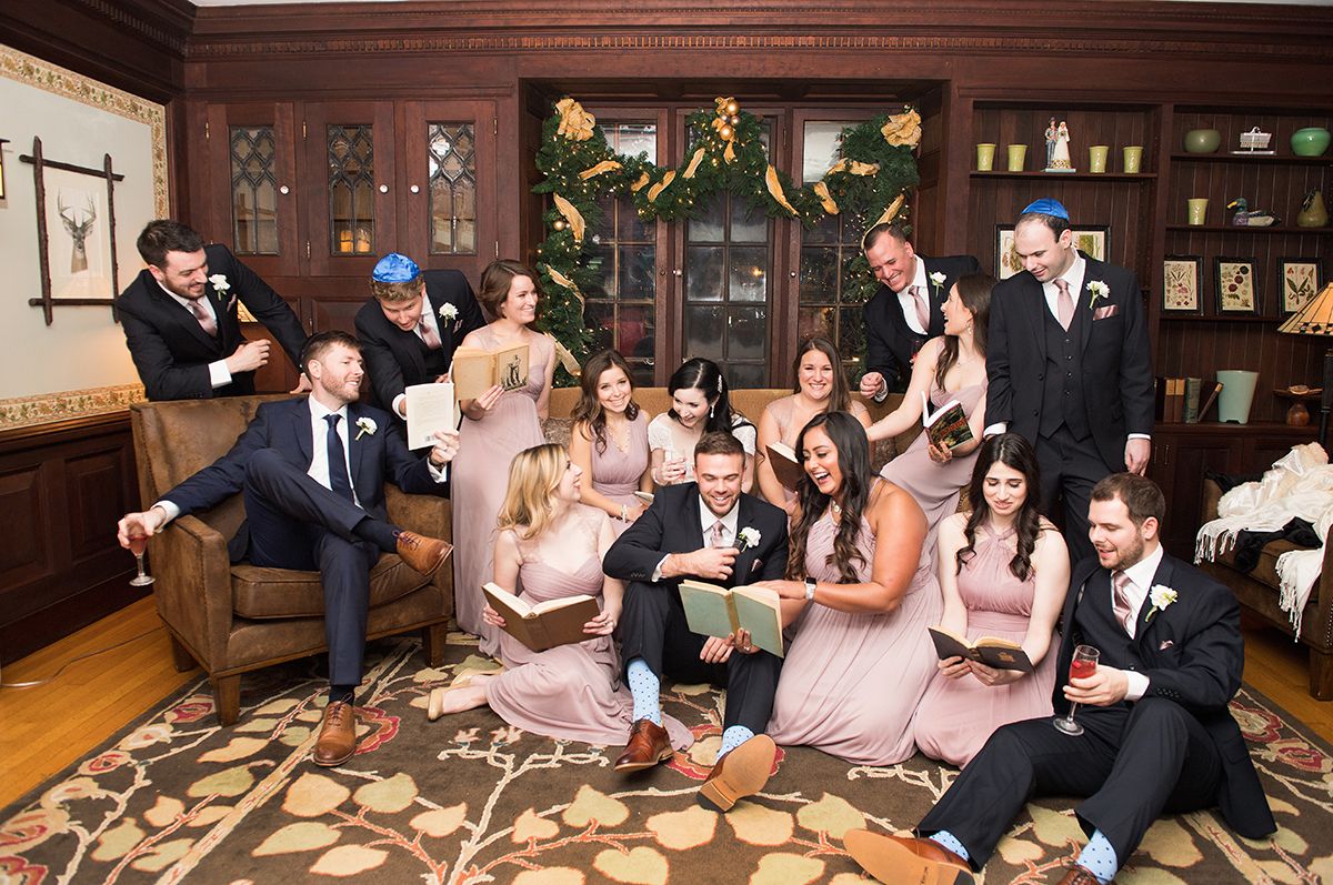 Wedding party sits together at a long rustic wooden table celebrating during the reception.