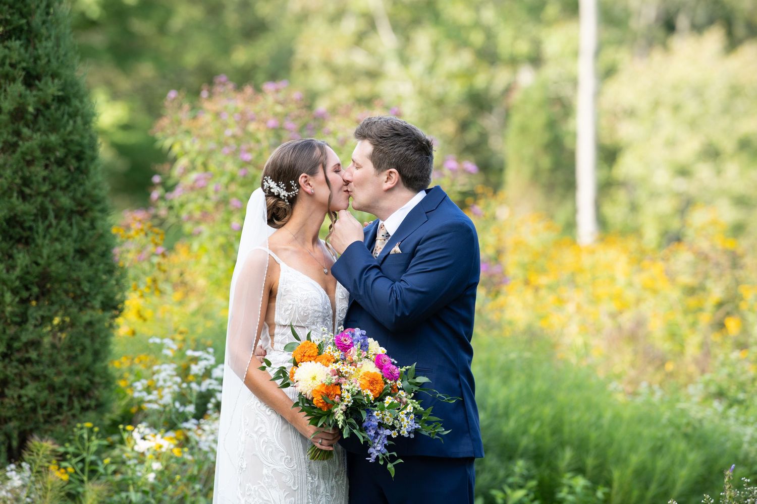 Romantic garden wedding portrait surrounded by vibrant wildflowers and natural landscaping.