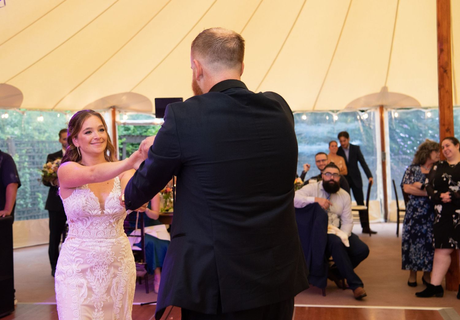 Couples dancing under a large white tent at an elegant evening reception.