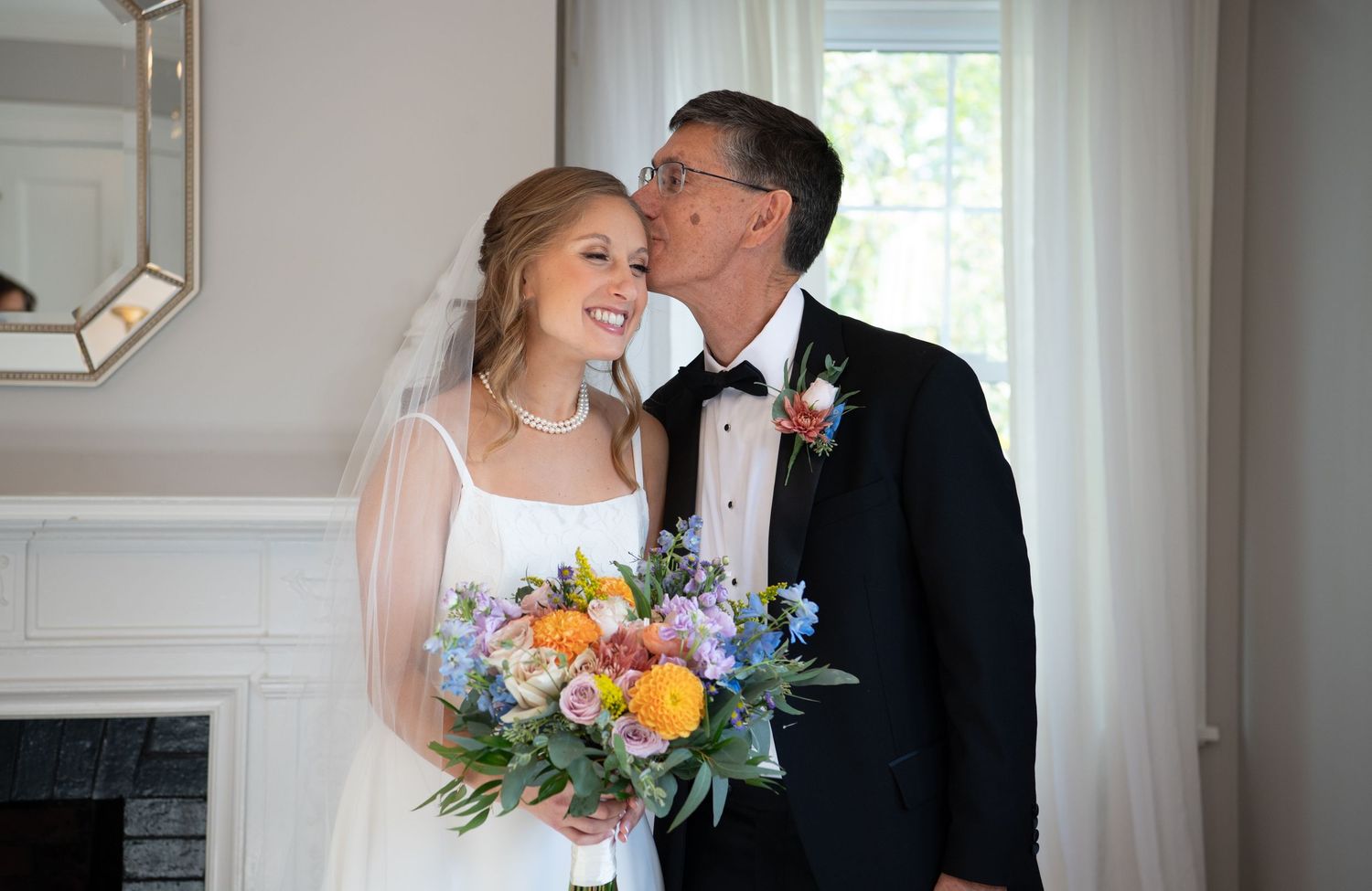 A couple shares an intimate moment in a bright white room with natural light streaming through windows.