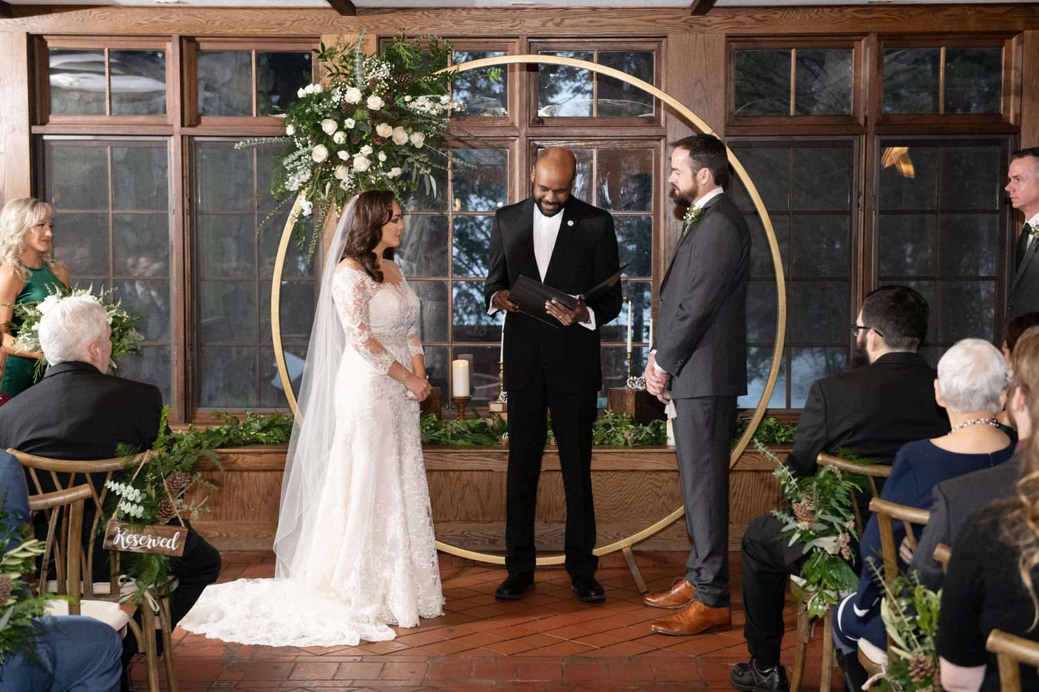 Wedding ceremony taking place in a rustic industrial venue with exposed brick walls and large windows.