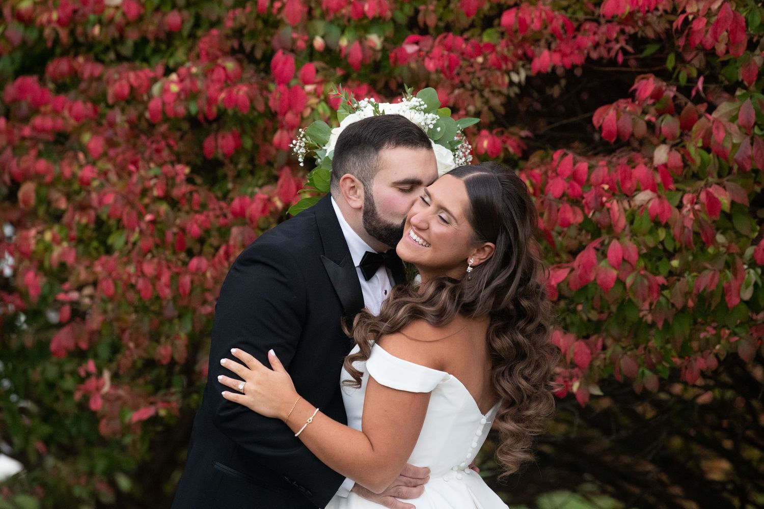 Couple sharing romantic moments among vibrant red autumn foliage.
