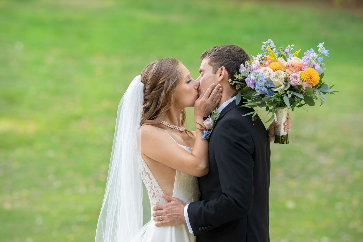 Romantic wedding couple shares tender moments in a lush garden setting with colorful floral bouquets.