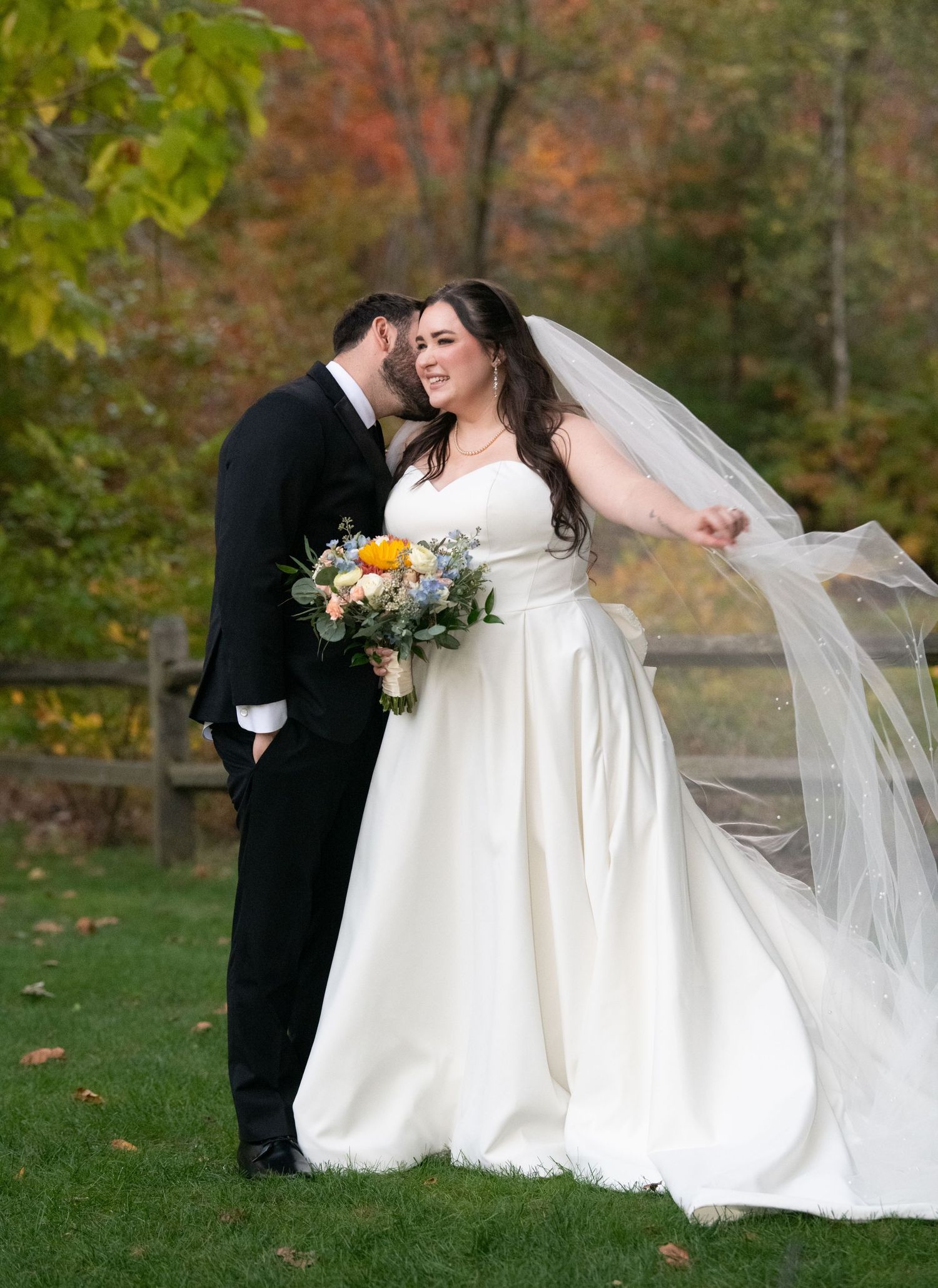 Newlyweds share romantic moments in a fall garden setting with vibrant autumn foliage and flowing white wedding dress details.