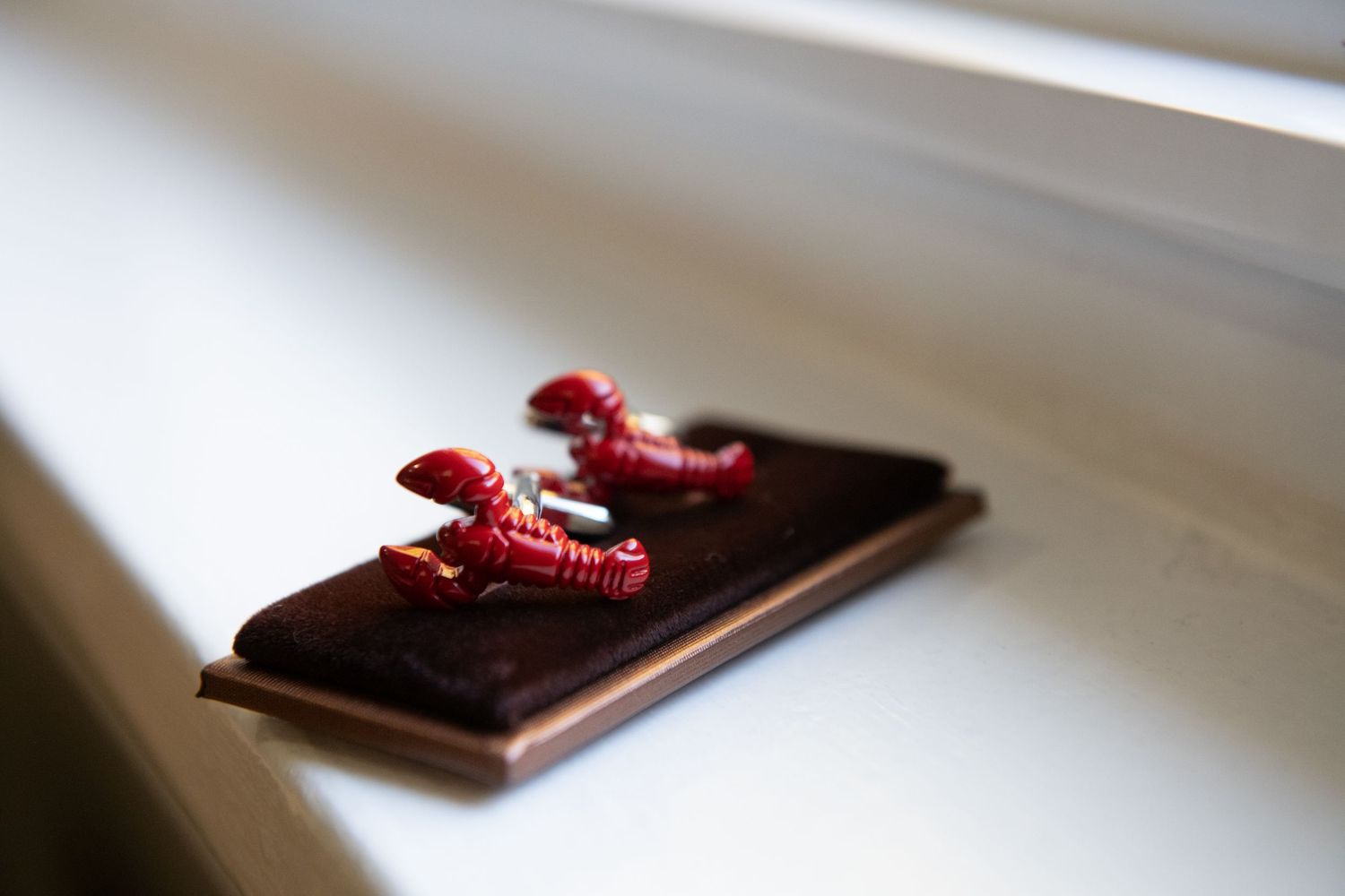 Red string earrings rest on a dark chocolate bar against a white surface in soft focus.