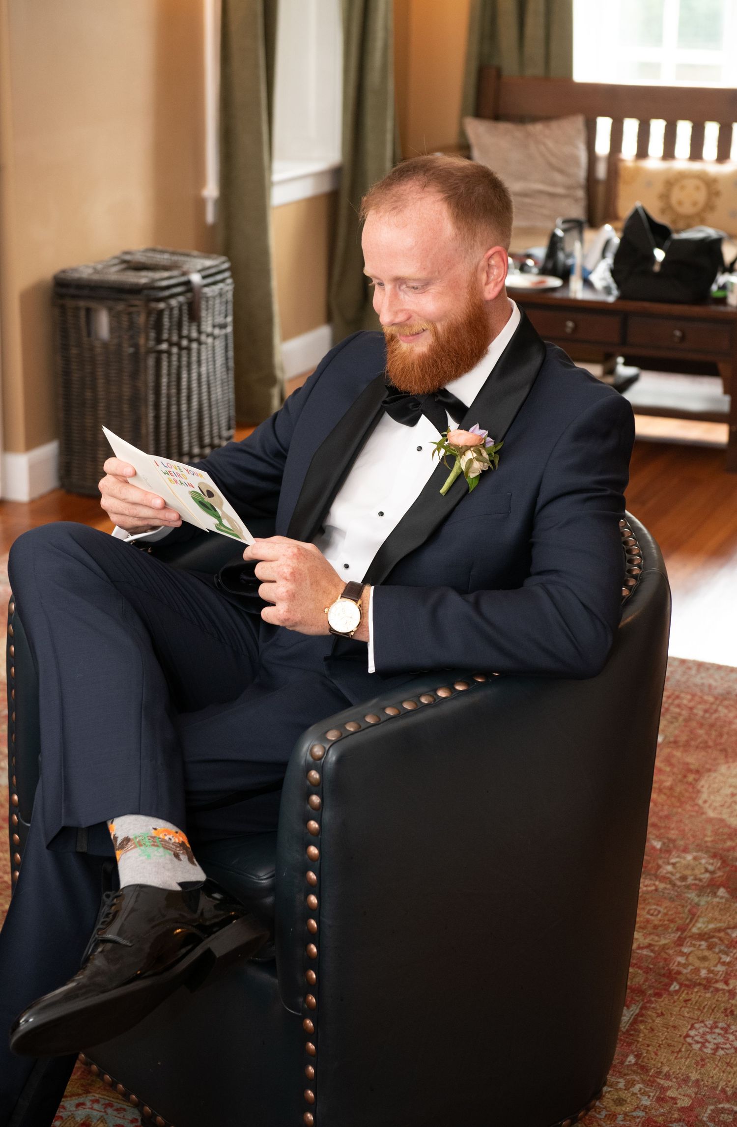 A formally dressed person reading a letter while seated in a studded leather armchair.