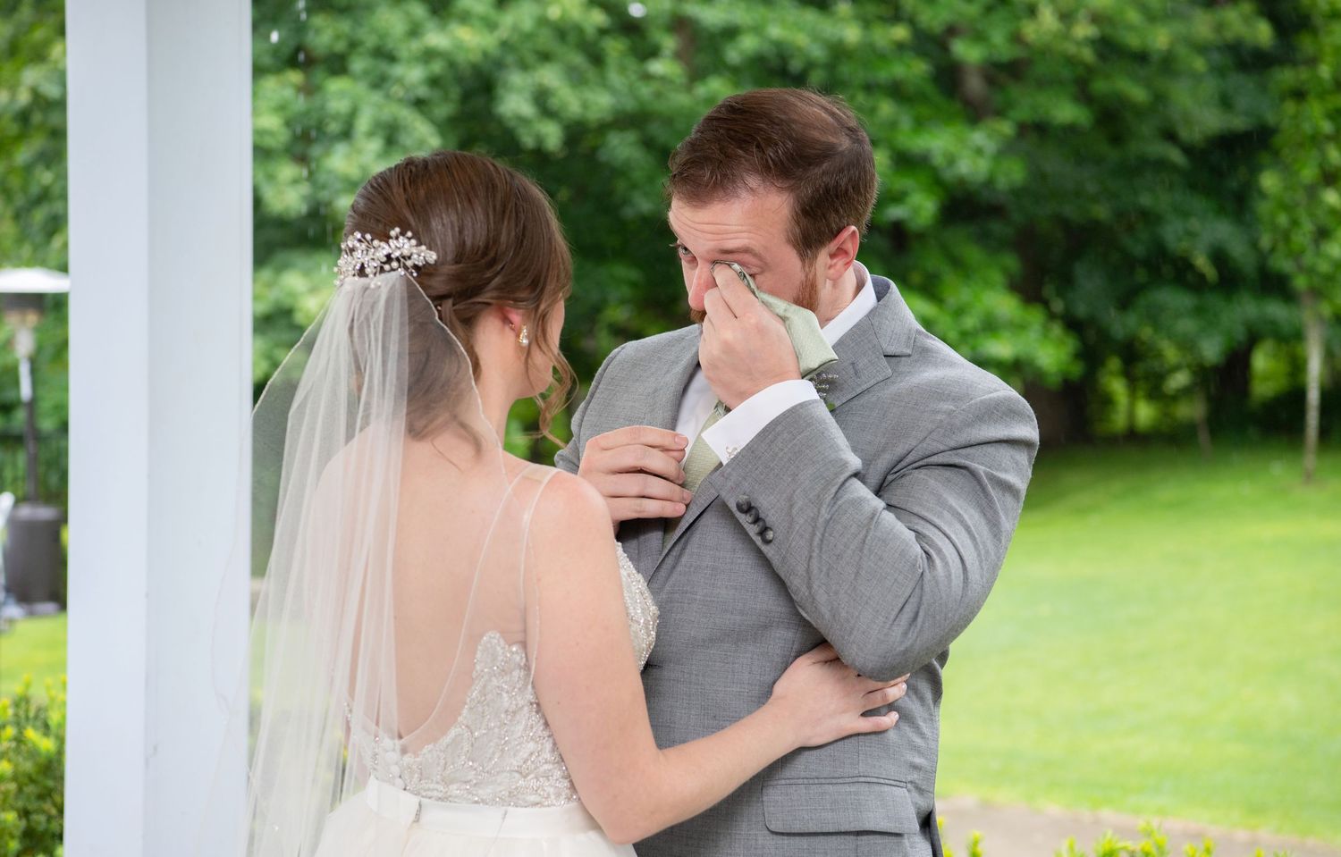 A romantic moment between newlyweds sharing a first dance under a white gazebo surrounded by lush greenery.