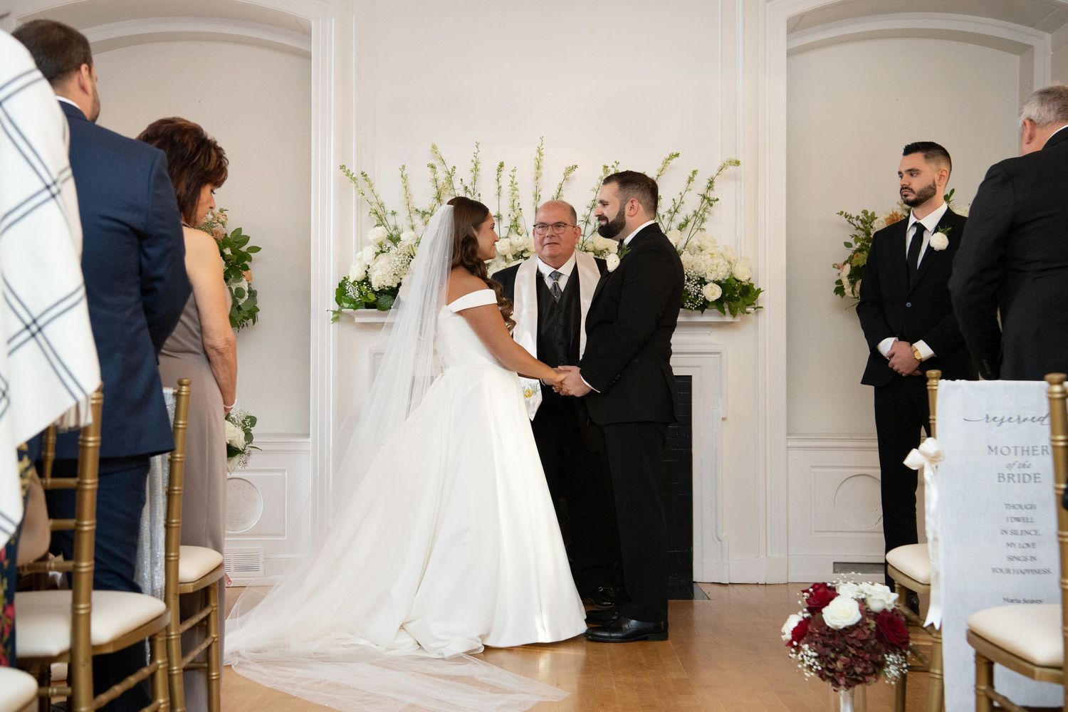 A wedding ceremony montage showing multiple angles of a bright white venue with elegant decor and floral arrangements.