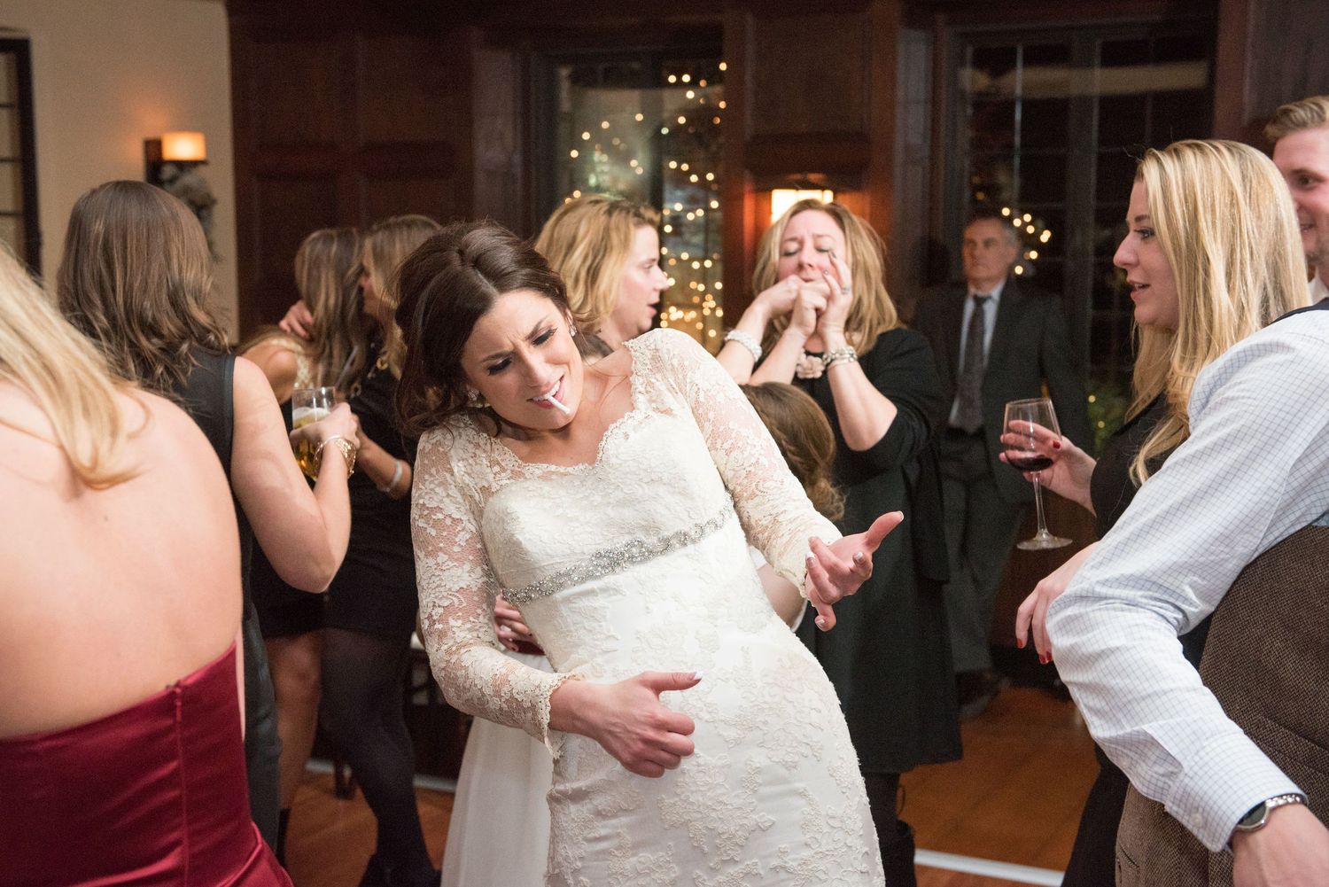 Wedding guests dancing and embracing on a dimly lit dance floor during a celebration.