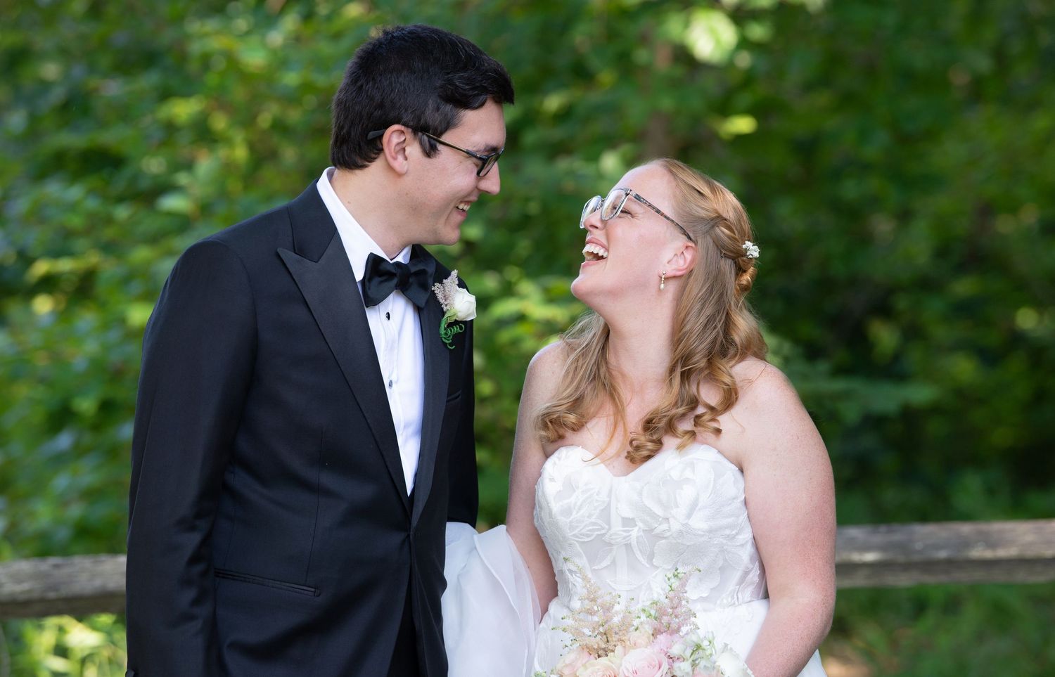 A couple in wedding attire share a romantic moment outdoors in a garden setting.