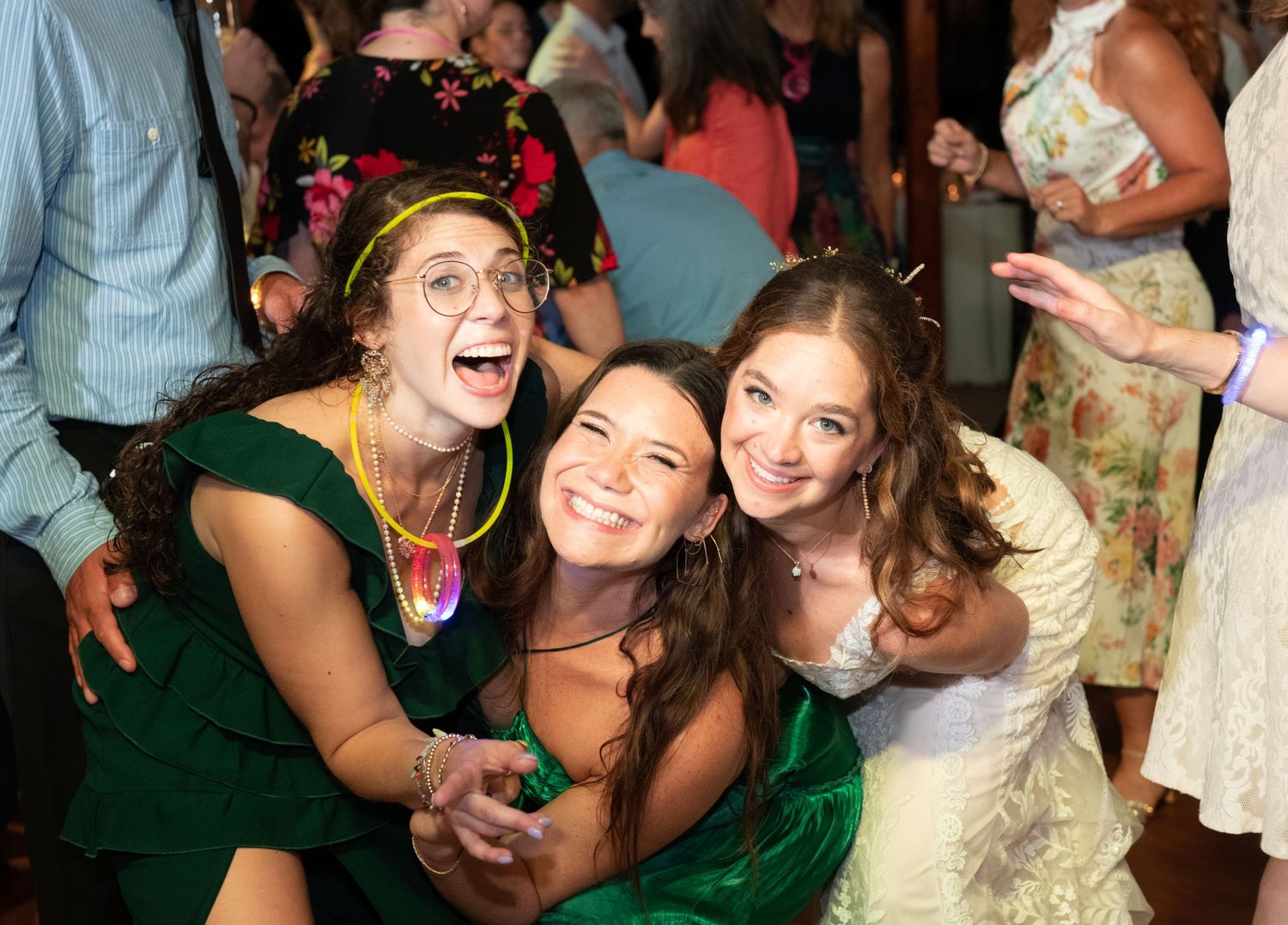 Wedding guests in colorful dresses share a joyful moment on the dance floor.