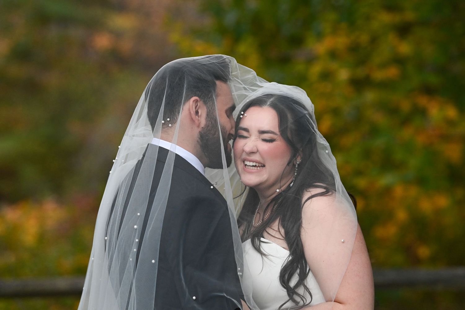 Romantic outdoor wedding moment captured with autumn trees in the background.