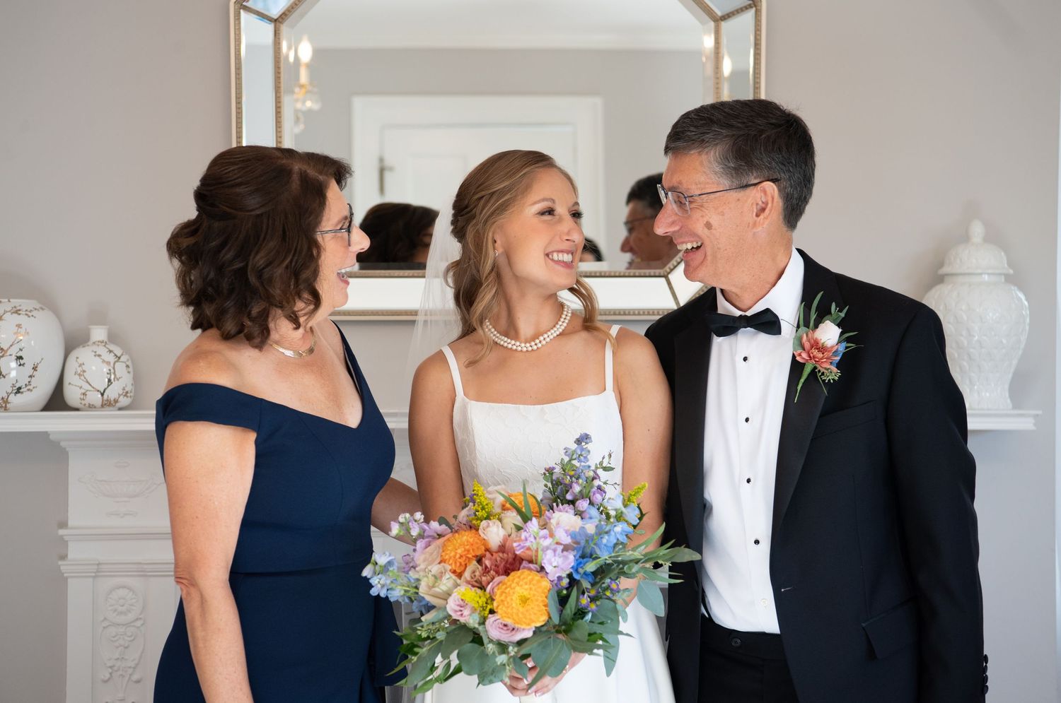 Wedding party members in navy blue and white attire share candid moments during formal photography session.