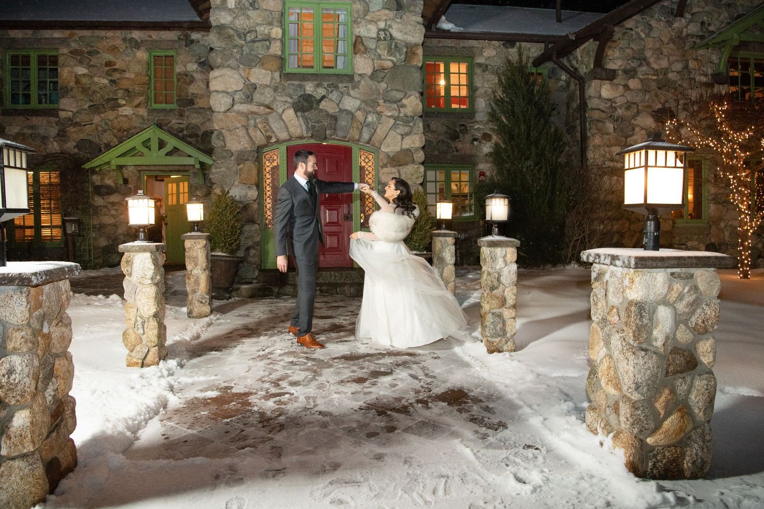 Snowy evening landscape of a stone building entrance with warm lighting and decorative columns.
