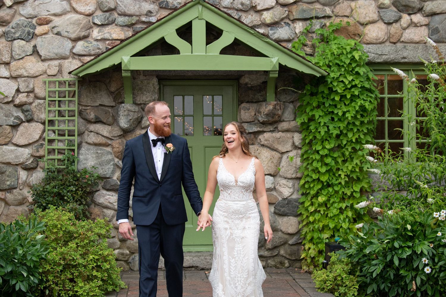 Elegant outdoor wedding ceremony in front of a stone building with green architectural details.