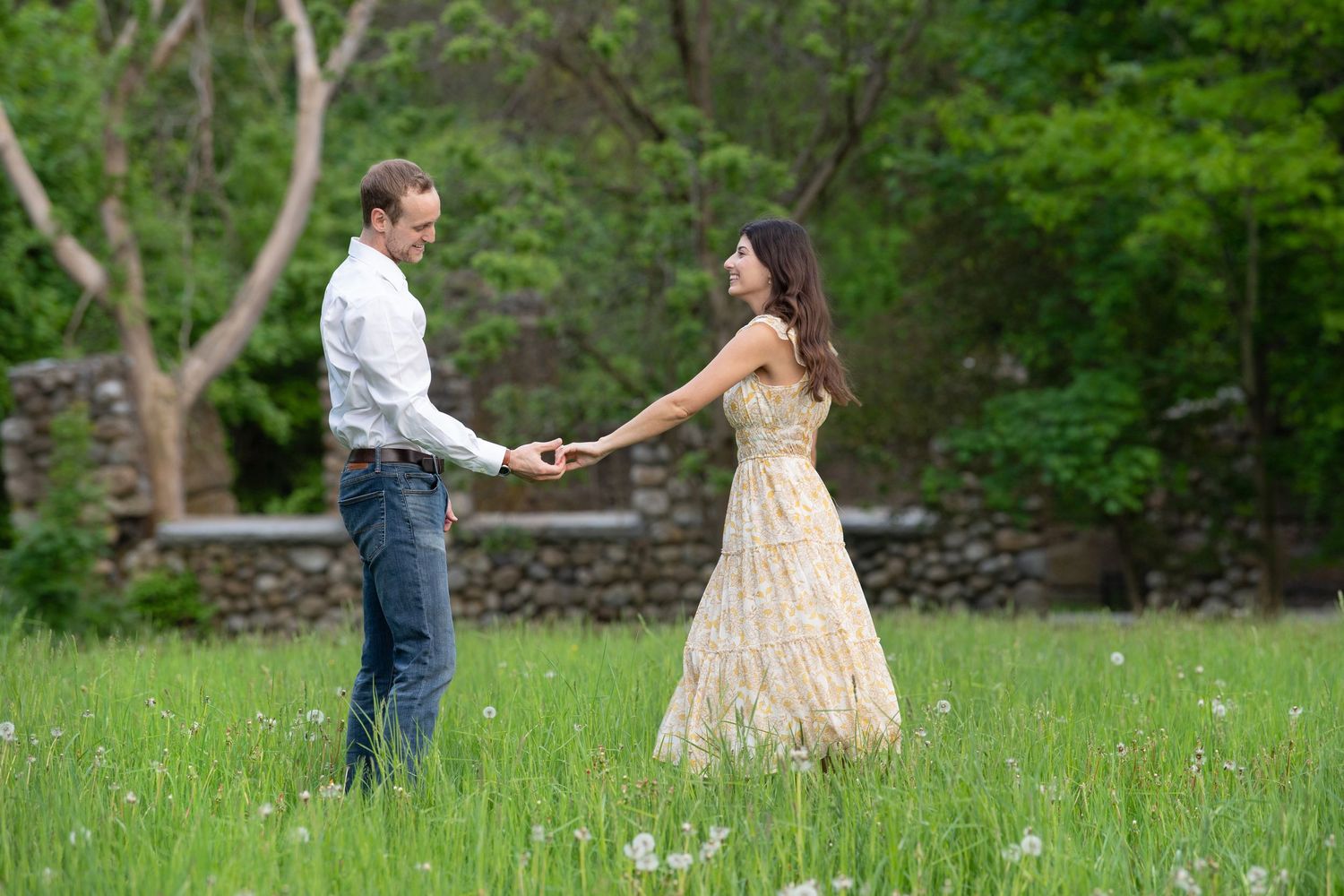 Two people dance together in a romantic twirl across a lush green field on a spring afternoon.