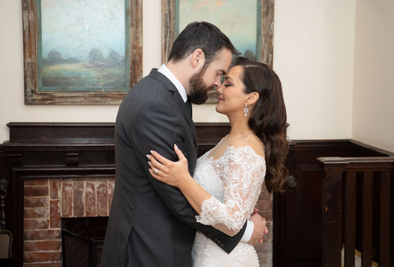 A romantic couple in wedding attire share an intimate moment while dancing in a vintage room.