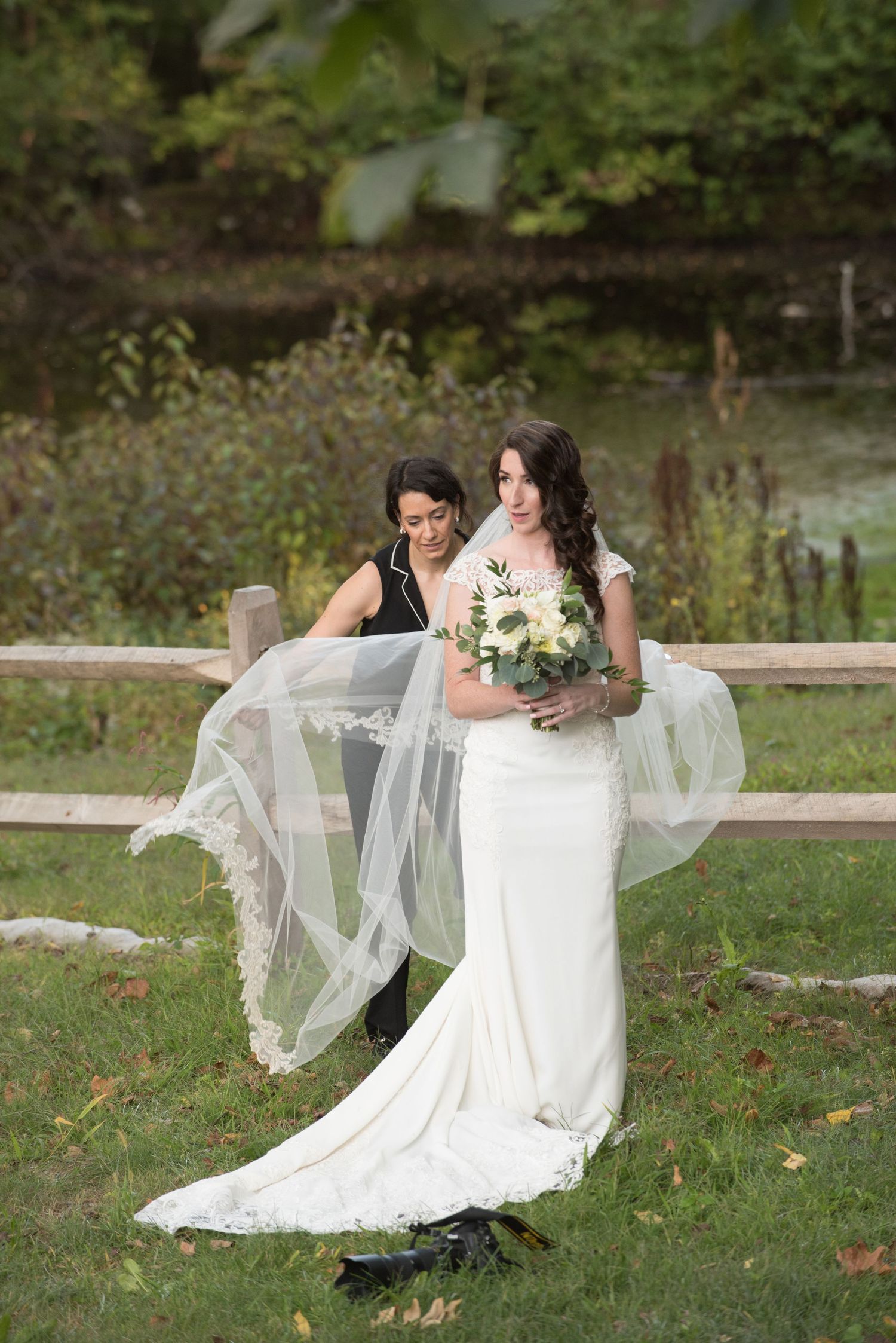 Elegant bridal portrait with flowing veil against autumn landscape backdrop.
