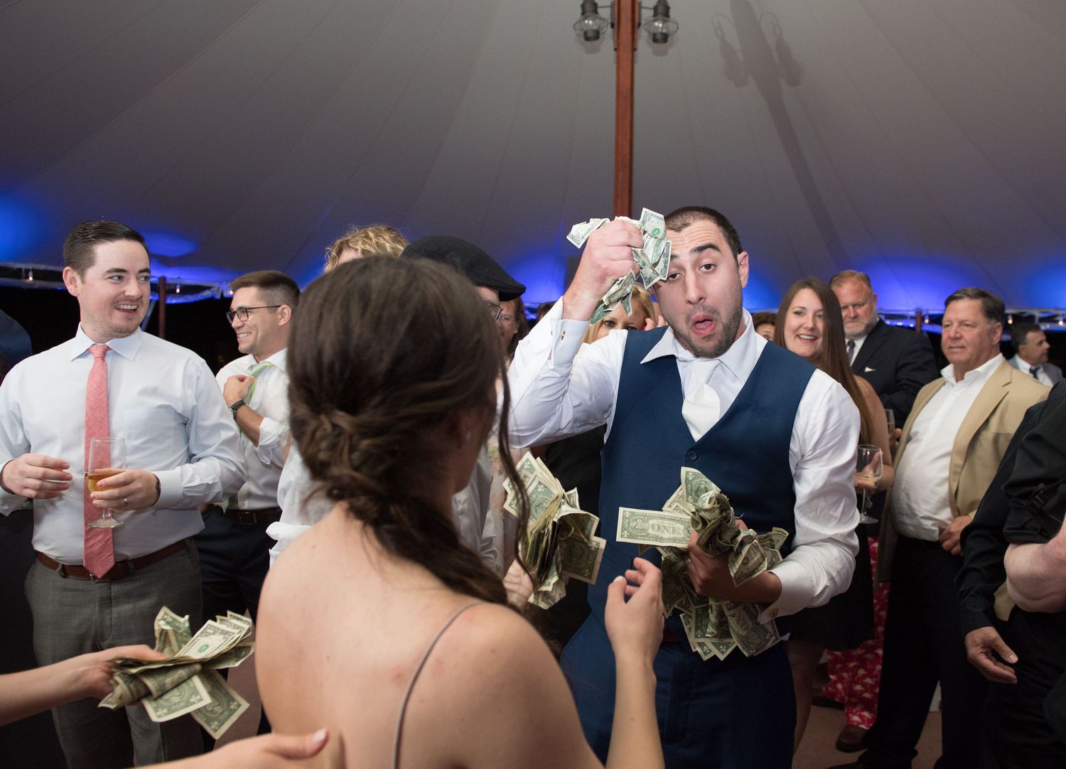 Dance party guests on a crowded dance floor celebrating with energetic movements under blue mood lighting.
