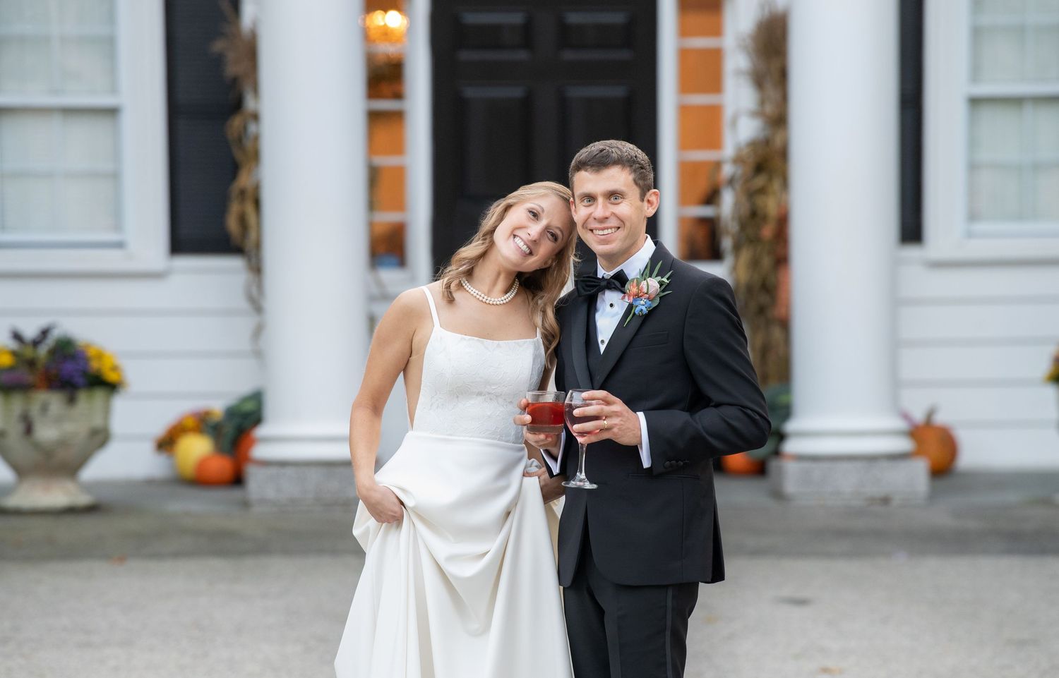 A happy couple shares joyful moments in formal wedding attire outside a white building with columns.