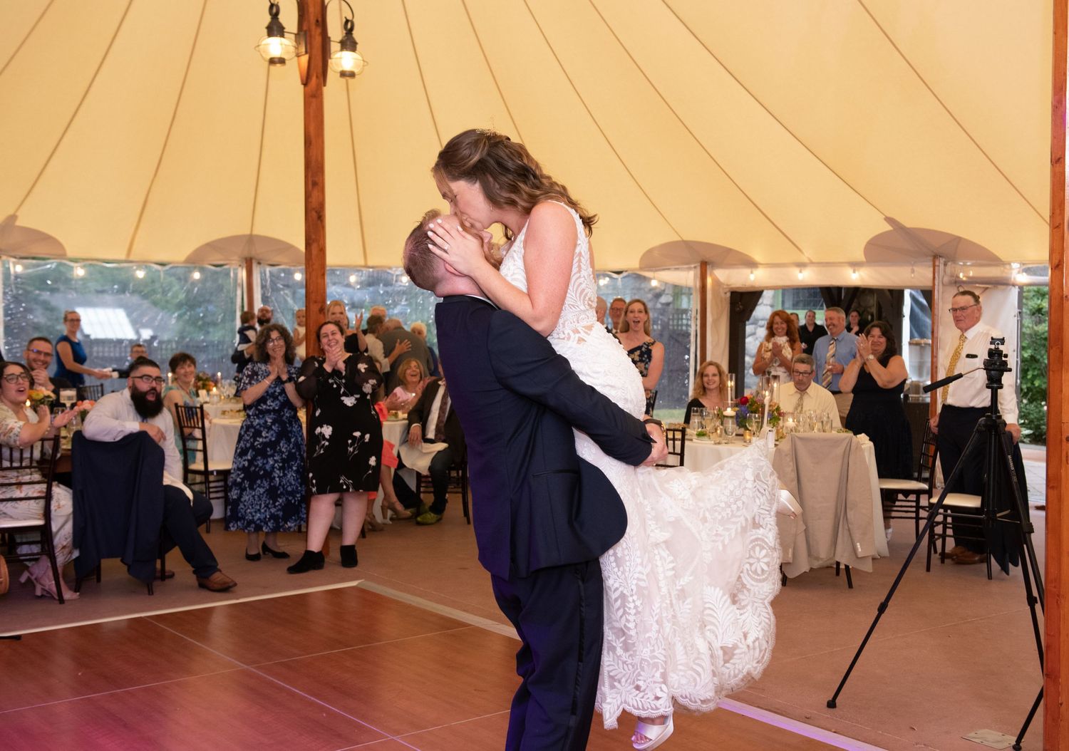 Wedding reception under a sailcloth tent with guests enjoying the celebration.