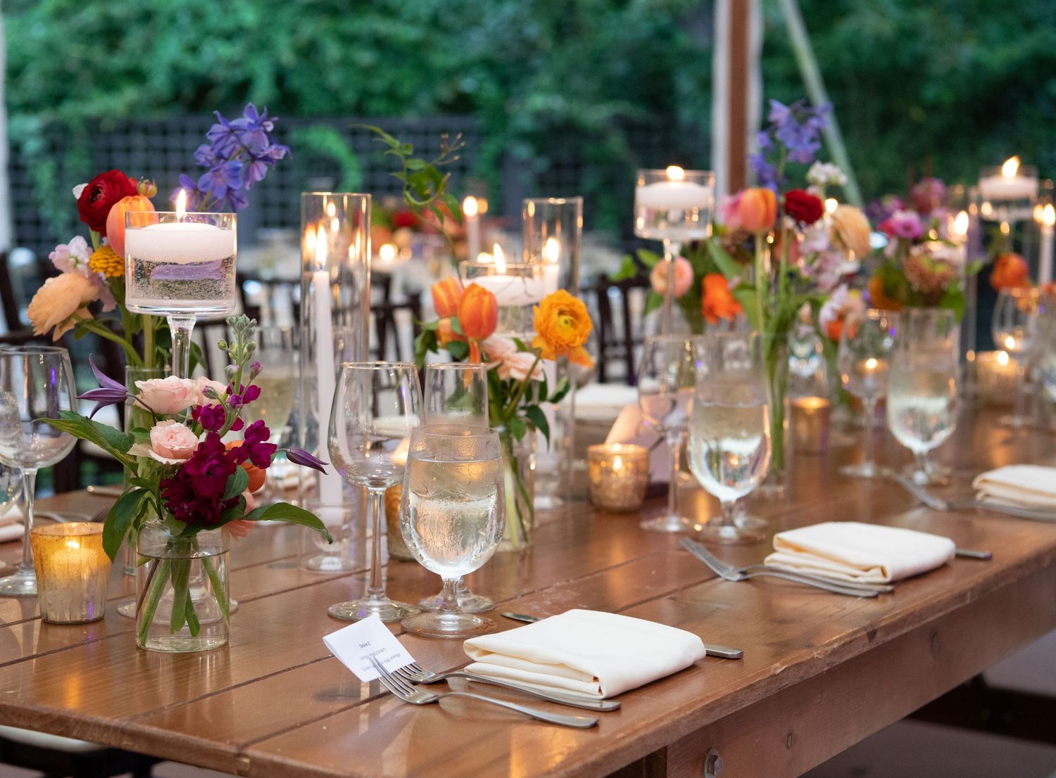 Wedding reception table set with colorful floral centerpieces and glowing candles.