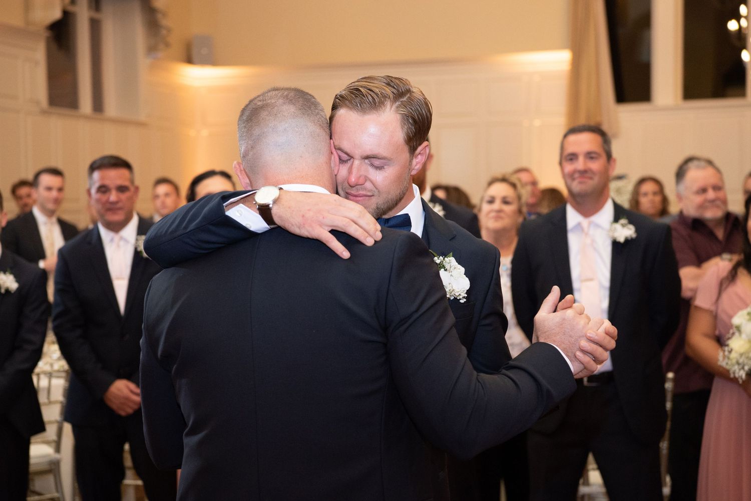 Wedding guests dance together on an illuminated dance floor at an elegant evening reception.