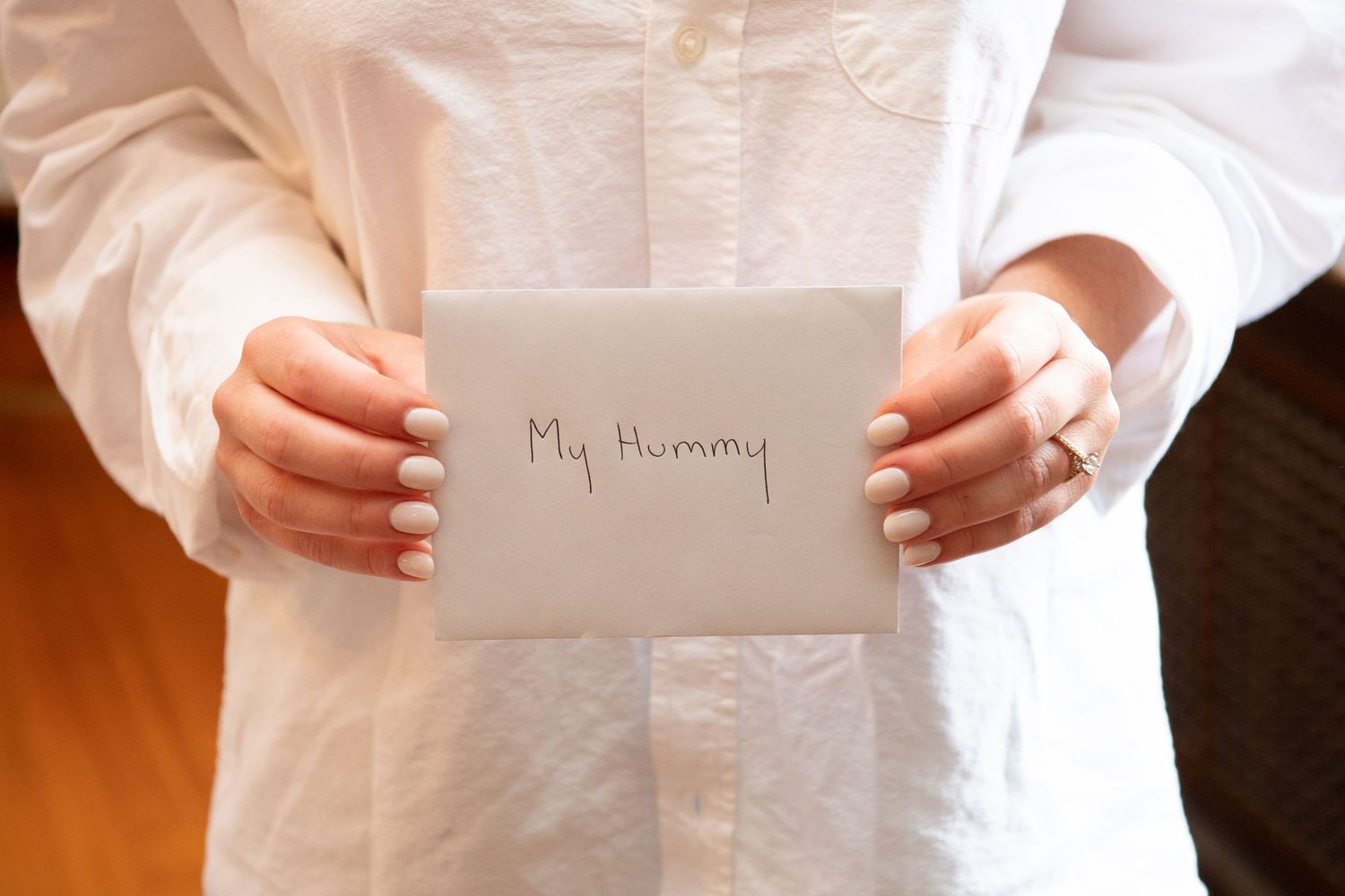 Hands holding a white envelope or note card with 'My Mummy' written on it.