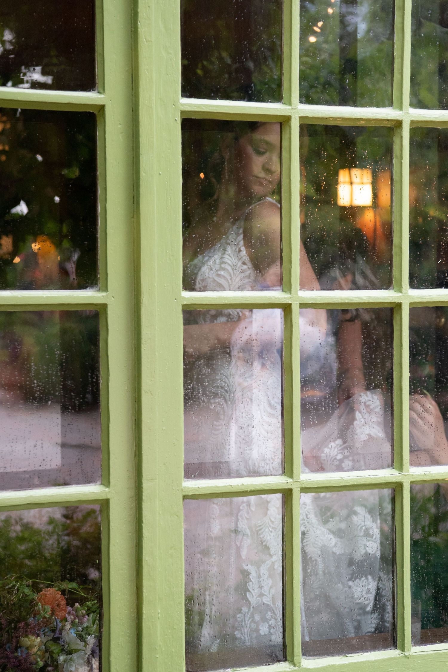Green window panes reflect wedding celebration scenes during evening reception.