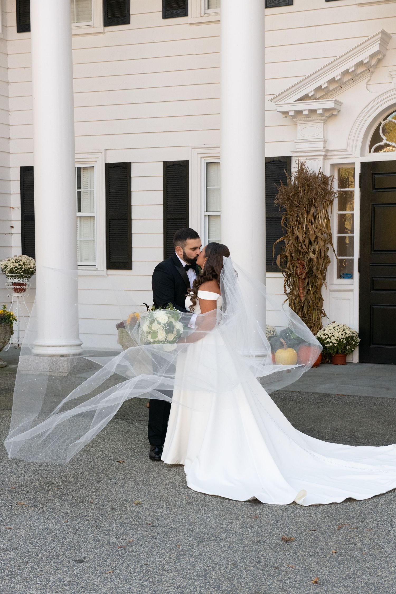 Wedding couple standing between white columns of a grand colonial-style building.