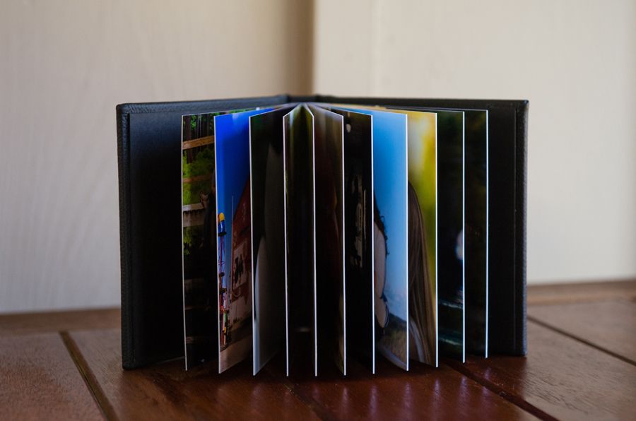 A small photo album with colorful pages stands open on a wooden surface, displaying vibrant blue and yellow tones.