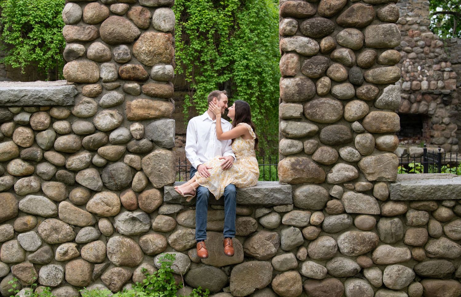 A series of candid photos showing affectionate moments against a rustic stone wall surrounded by greenery.