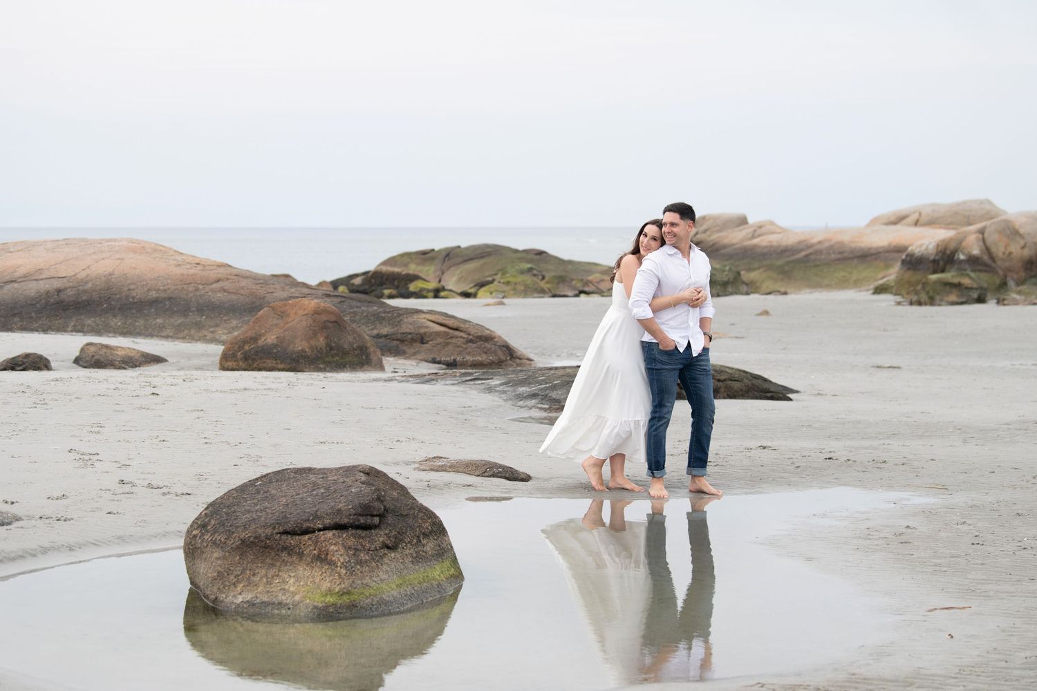 Coastal wedding photography with rocky beach landscape and dramatic cloudy sky.