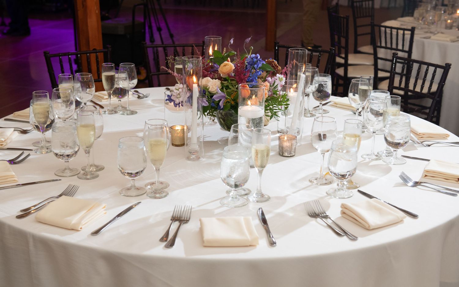 Wedding reception tables set with white linens and place settings in an elegant banquet hall.