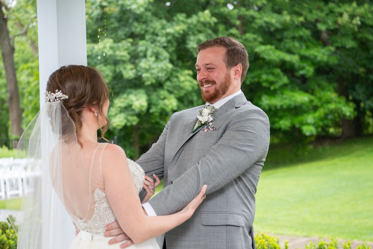 Couple shares joyful first look reaction on their wedding day under an outdoor pavilion.