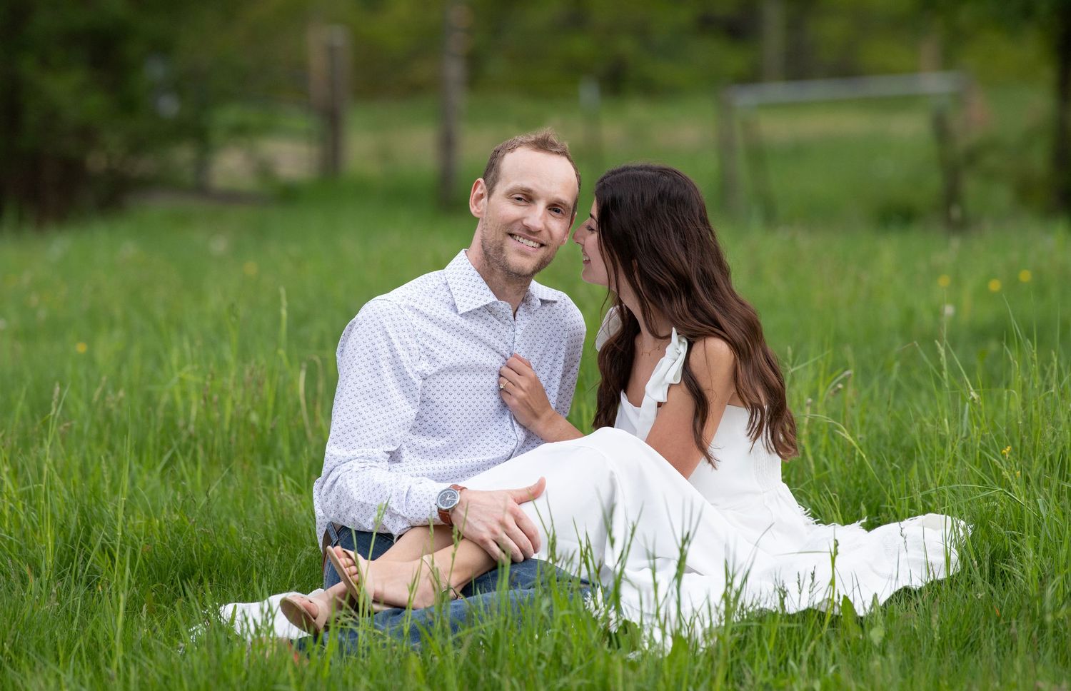 Romantic couple enjoys a casual picnic while lying in a lush green grass field on a sunny afternoon.