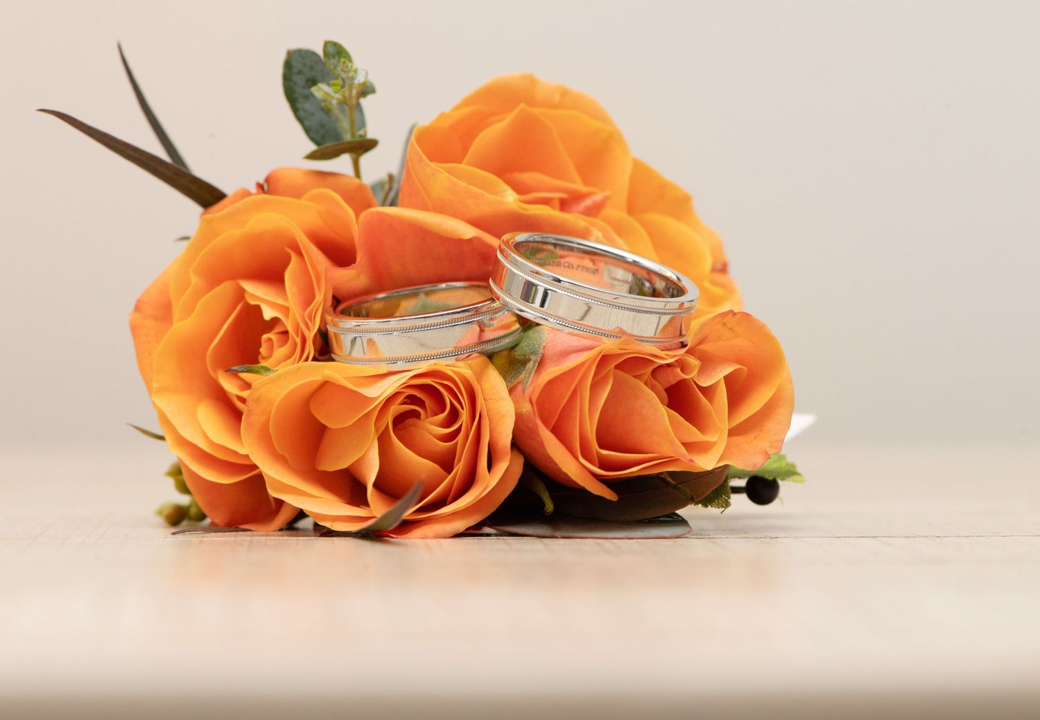 Fresh orange roses lying on a white surface in a row with soft natural lighting and shadows.