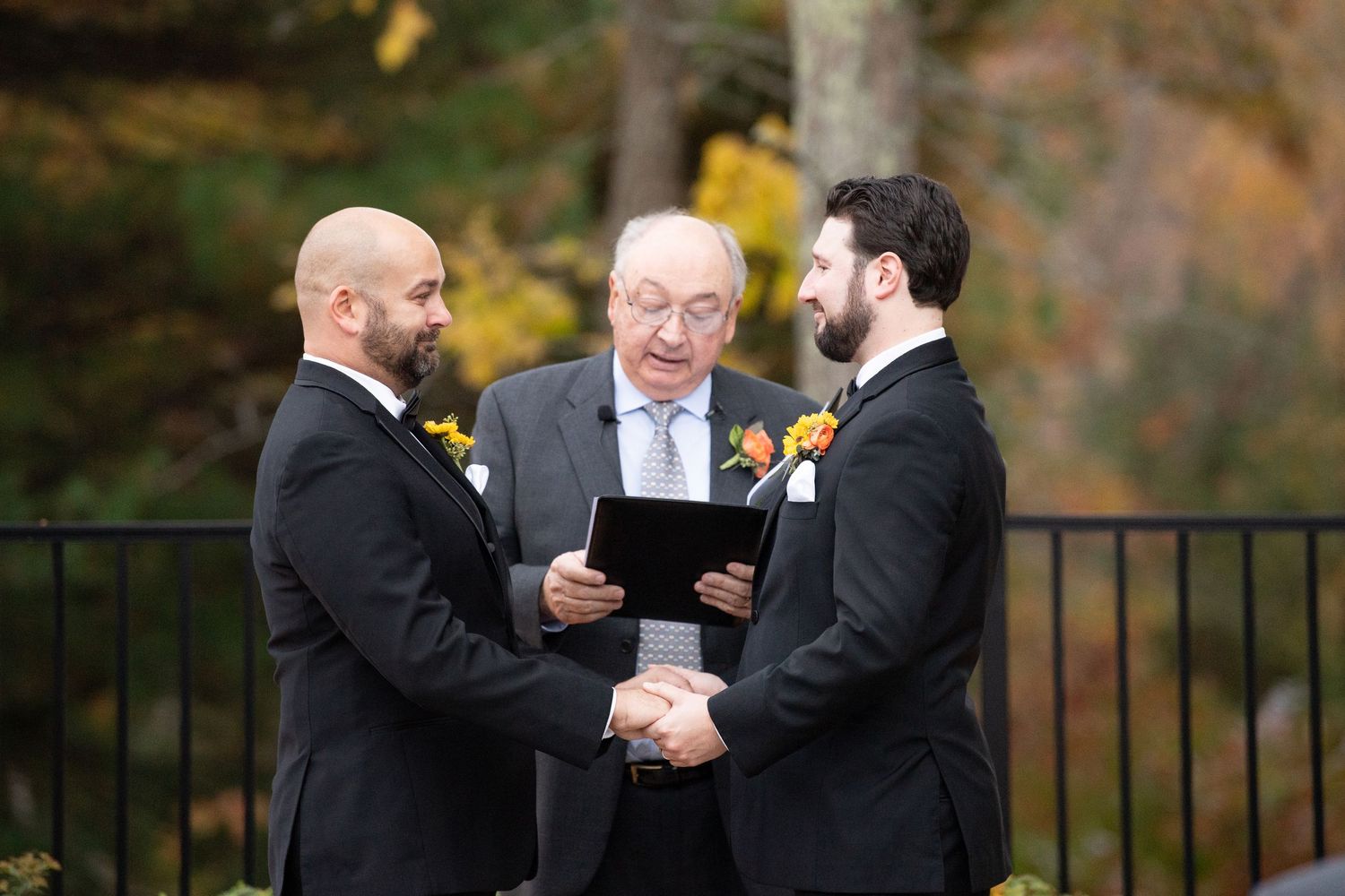 Wedding ceremony guests share joyful laughter and smiles during an outdoor autumn celebration.