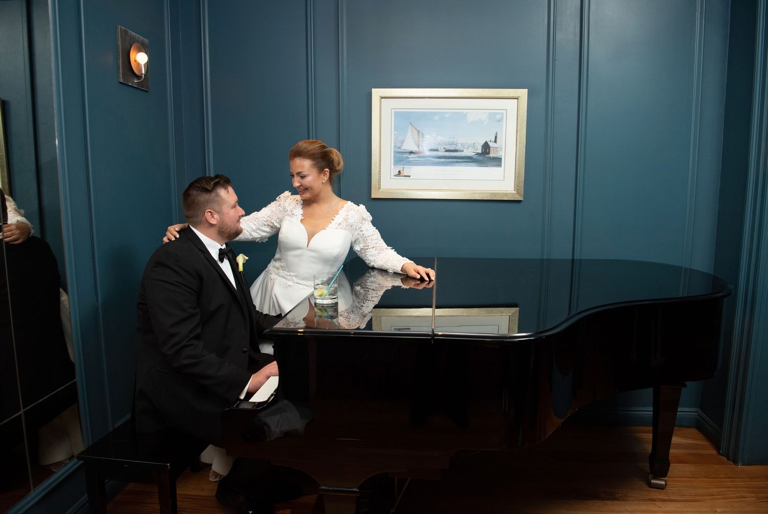 People in formal attire having a conversation in a room with teal blue walls and framed artwork.